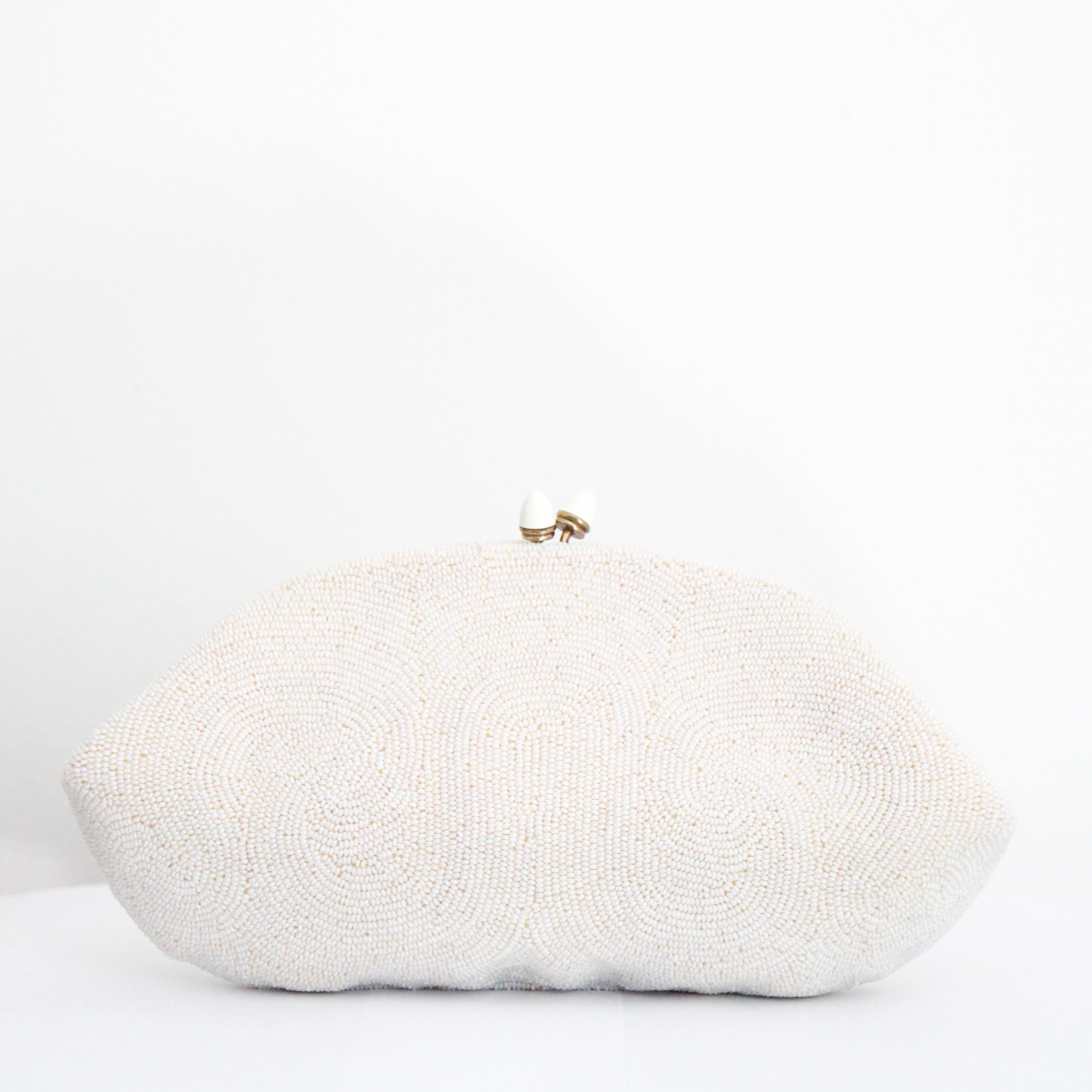 This intricately beaded 1950's clutch bag, on a base of white cotton voile, embellished with a swirling pattern of pearlescent rocaille beads in an undulating design, is the perfect finishing touch to your outfit. The concealed frame features a kiss