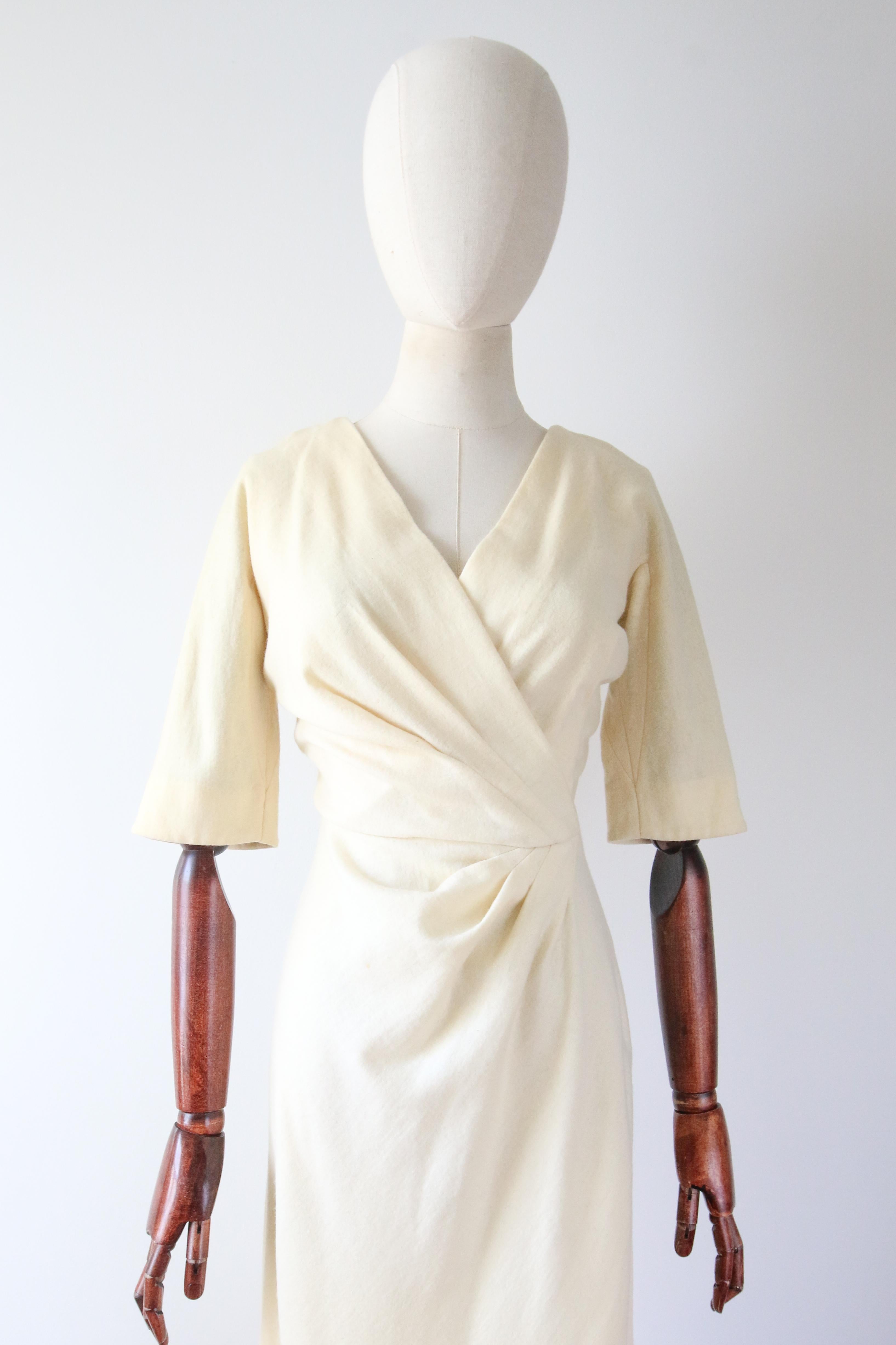 Rendered in a classic silhouette, this original 1950's cream wool dress, with delicate pleated details, is just the piece for your timeless collection. 

The V shaped neckline boasts a cross over cut, which joins the front left hand side of the