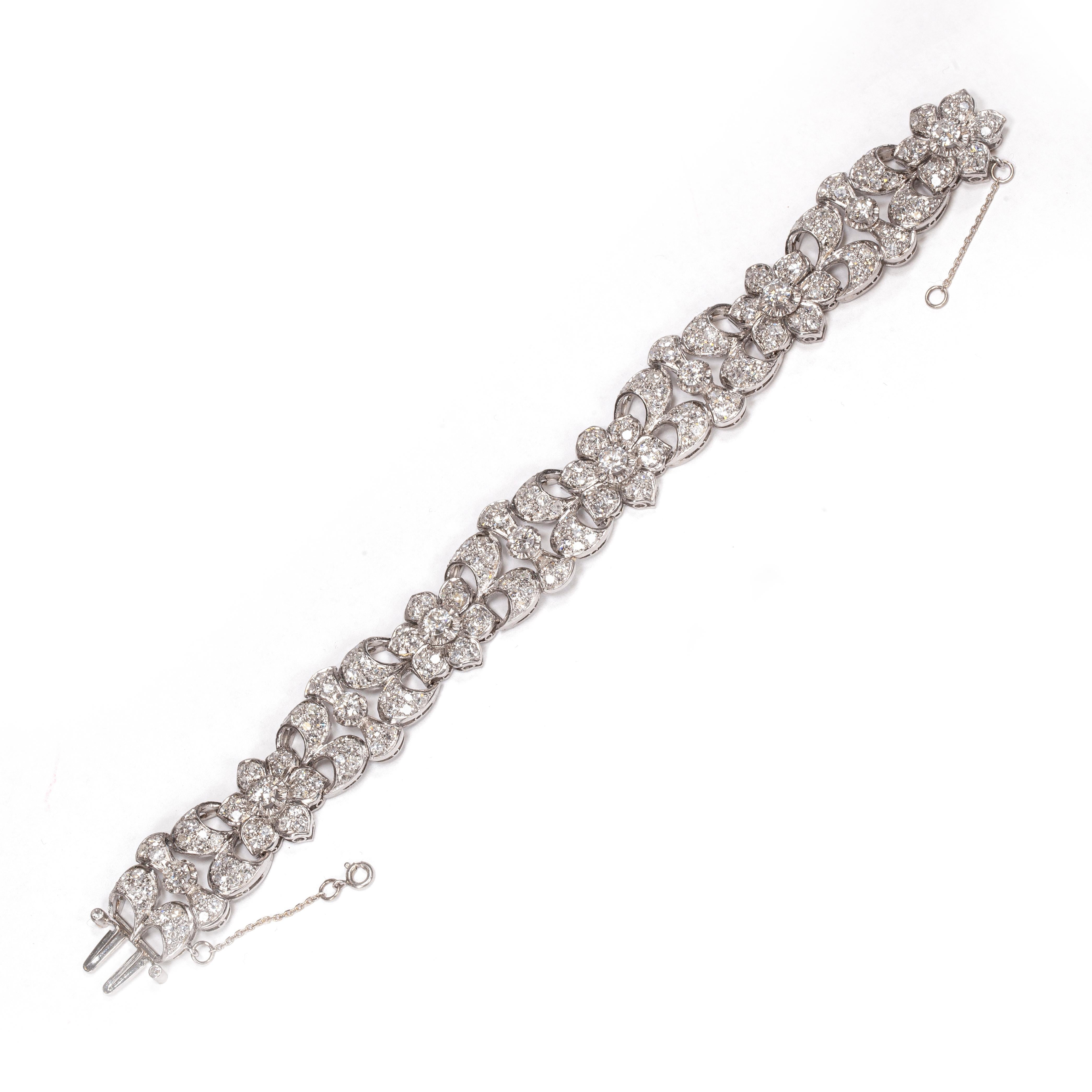 This beautiful 1950s platinum and diamond floral bracelet is truly one of a kind. 10 transitional cut diamonds are set in individual raised settings, against a gorgeous backdrop of pavé set eight cut diamonds of generous proportions. In total, this