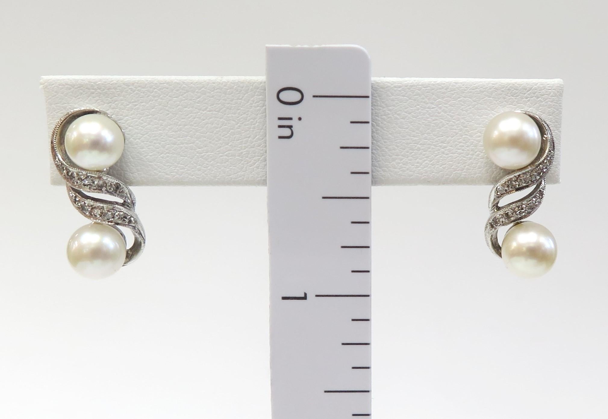 Elegant 1950s double pearl earrings with glittery Diamond ribbon swirls.

14 Karat white gold
Pearls: 7mm
20 Single Cut Diamonds total weight: 0.24 Carat (5 stone chipped - can not see with naked eye)
5.8 Grams
Length: 3/4 inch
