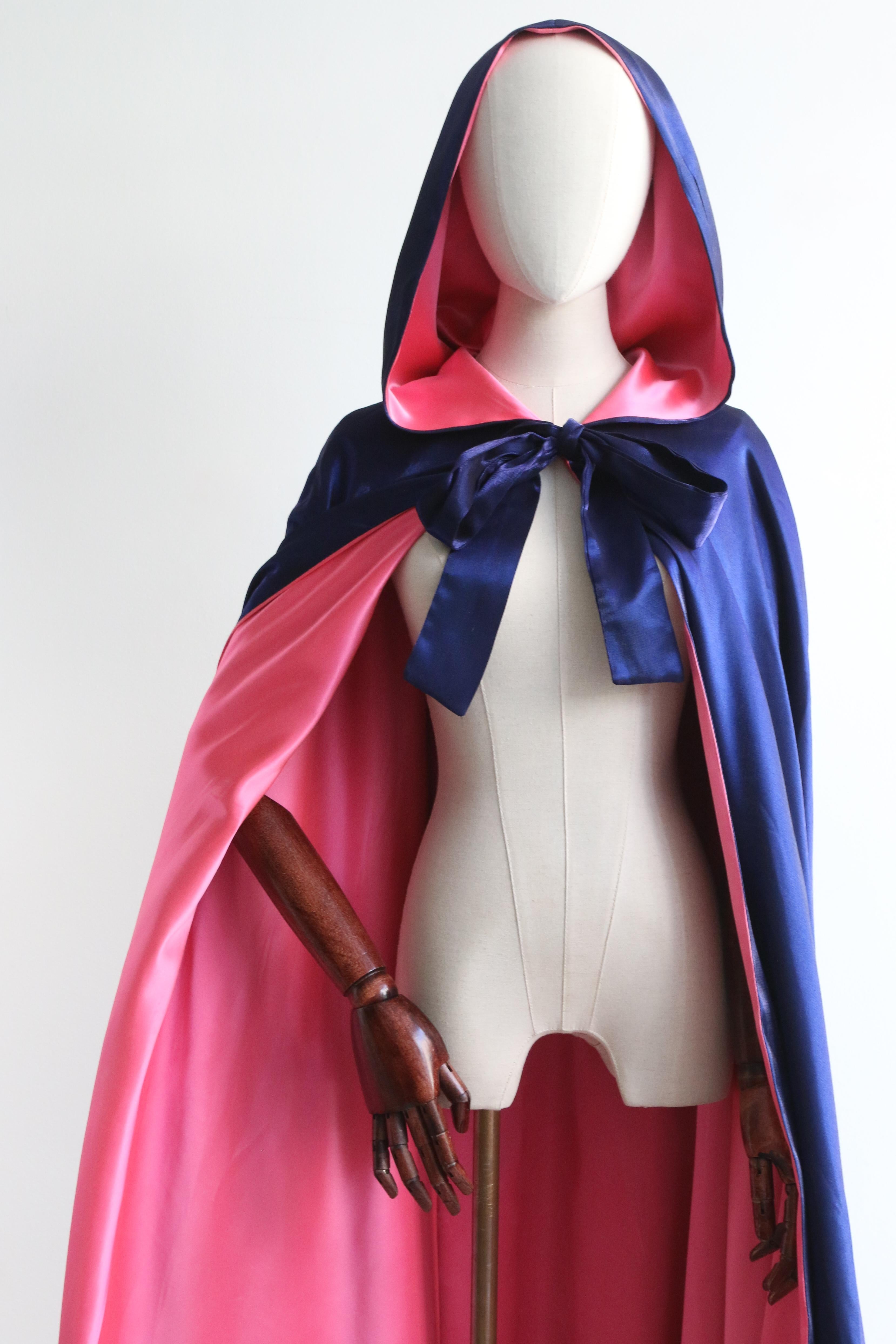 The most majestic and eye-catching cape you could ever set your eyes upon. Rendered in a hot pink satin lining and a sparkling silk midnight blue outer-layer, this 1950's evening cape is the perfect statement to your evening wardrobe.  

The simple