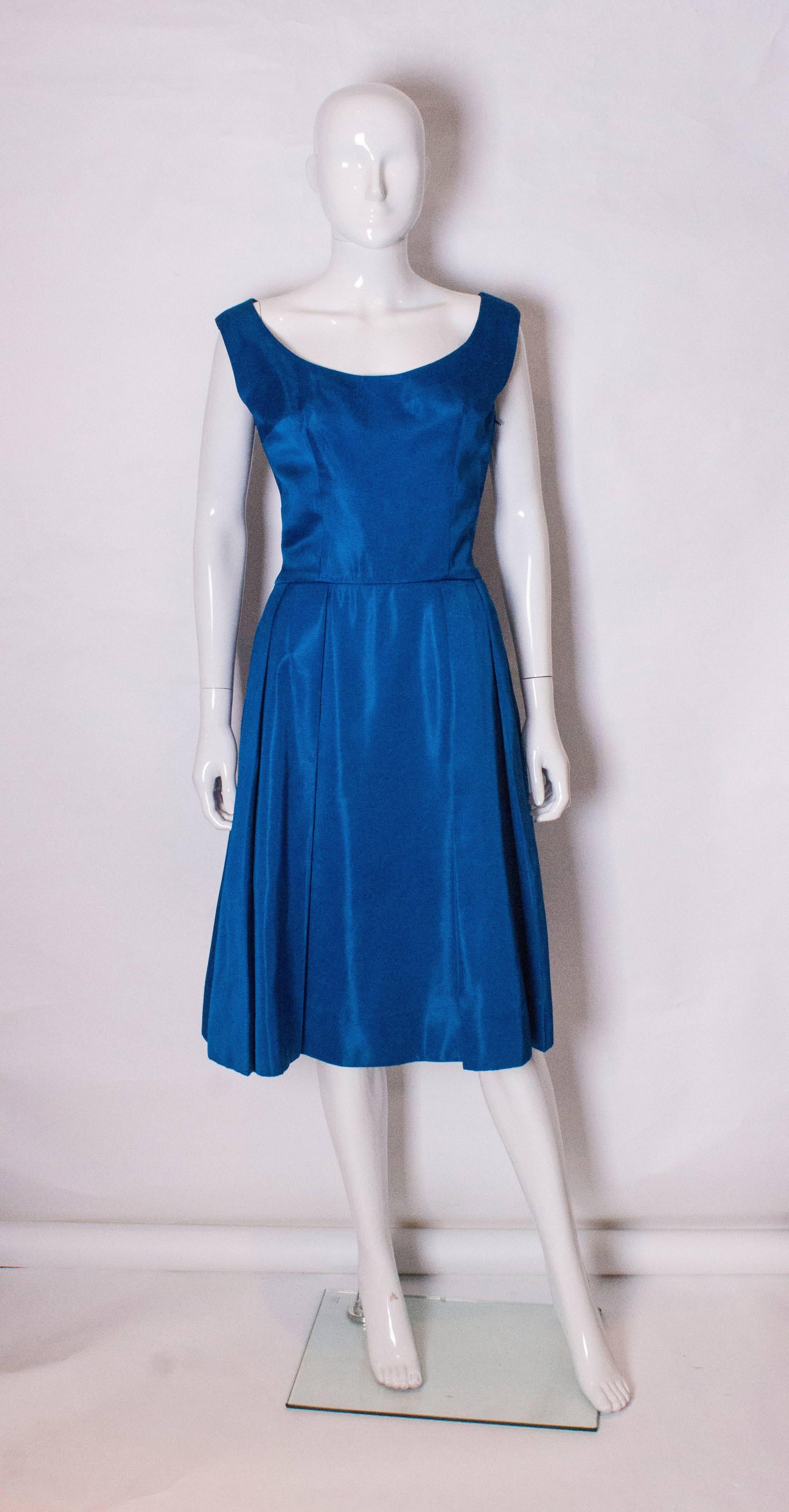 A charming and chic cocktail dress from the 1950's. In a wonderful electric blue colour, the dress has a scoop neckline at the front , and a deep v neckline at the back. The dress has a tail of fabric at the back.