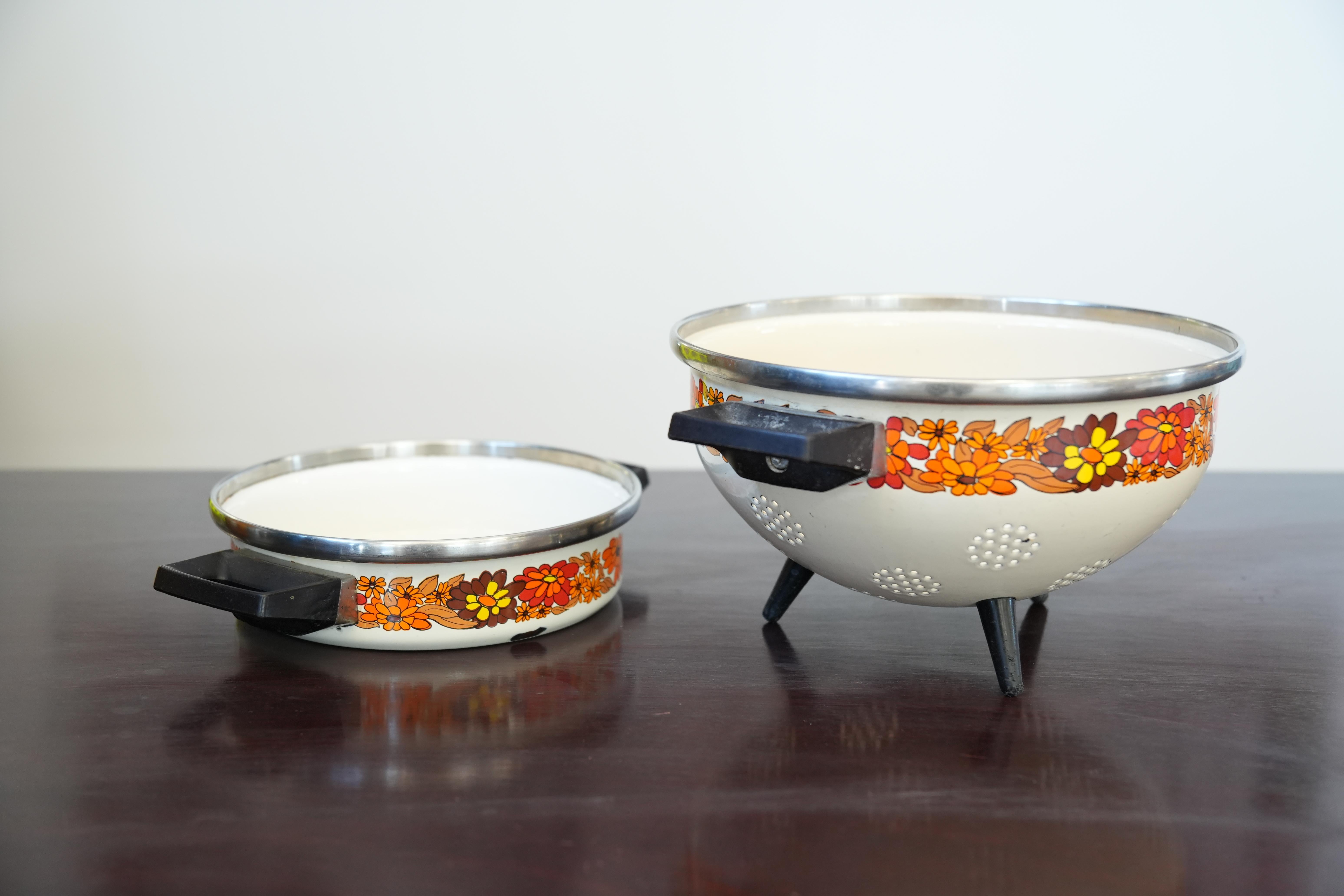 Elevate your kitchen with this charming mid-century duo: an enamel-coated colander and matching stew pot, both adorned with a warm retro floral band. Perfect for collectors and home cooks seeking authentic 1950s flair and functional design.

Key