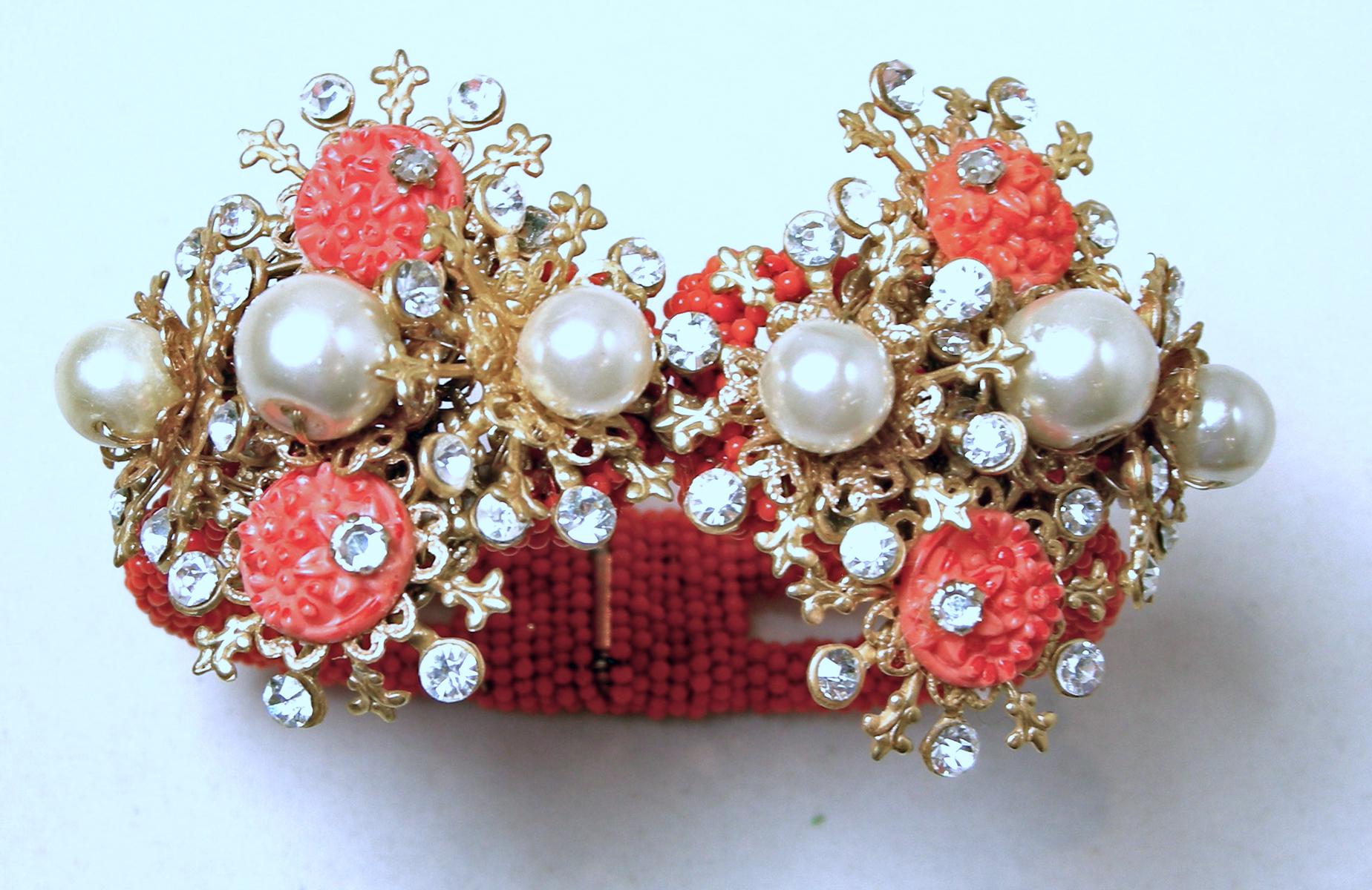 This vintage 1950s bracelet features faux coral beads with faux pearl with crystal accents in a gold tone setting.  In excellent condition, this clamper bracelet measures 6-1/2” around the inside x 1-3/4” wide at the front.