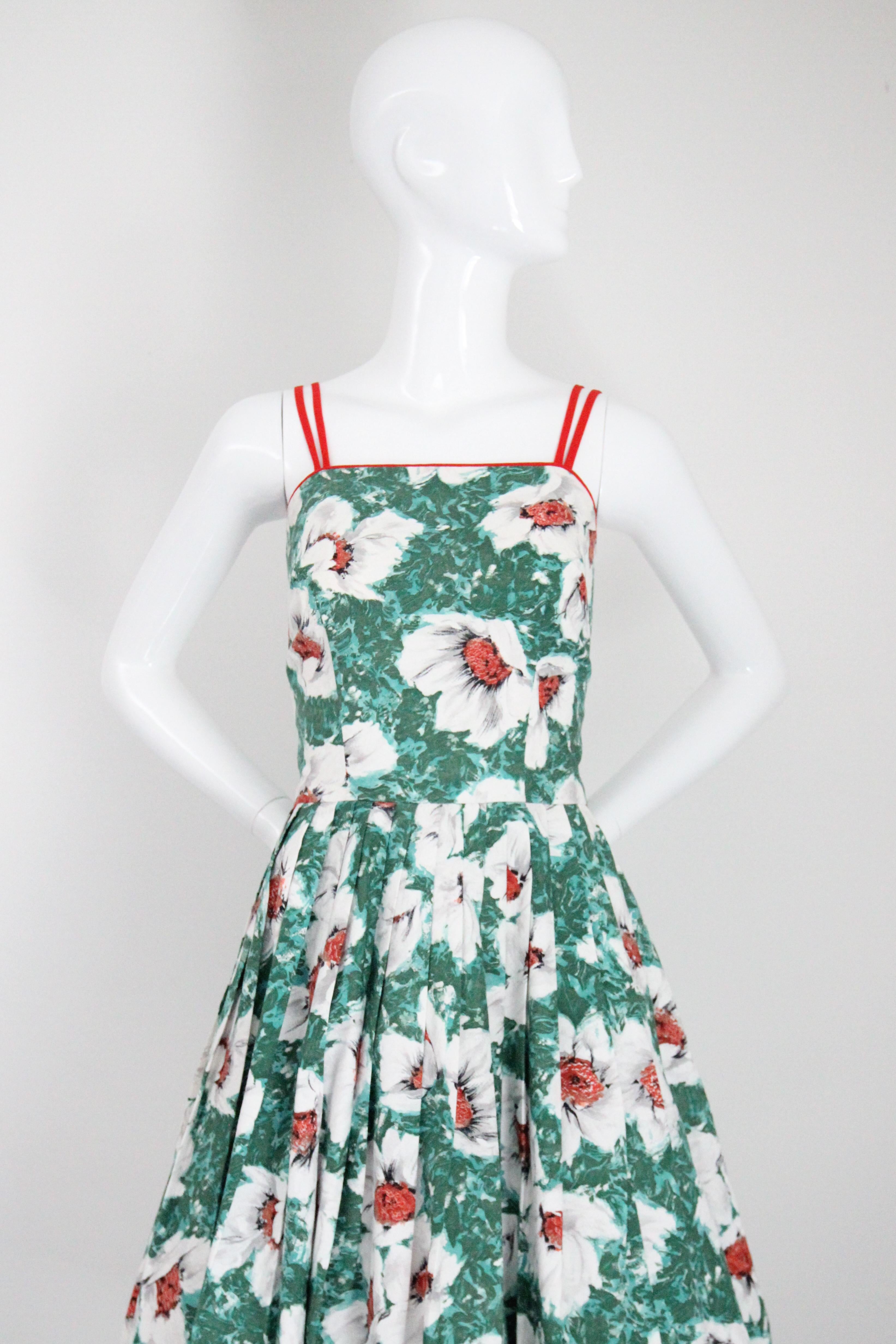 Rendered in the most eye-catching combination of greens and reds, in a brushstroke floral design, this original 1950's brocade cotton day dress, is just the piece to welcome the warmer weather with. 

The straight cut neckline is framed by a bold