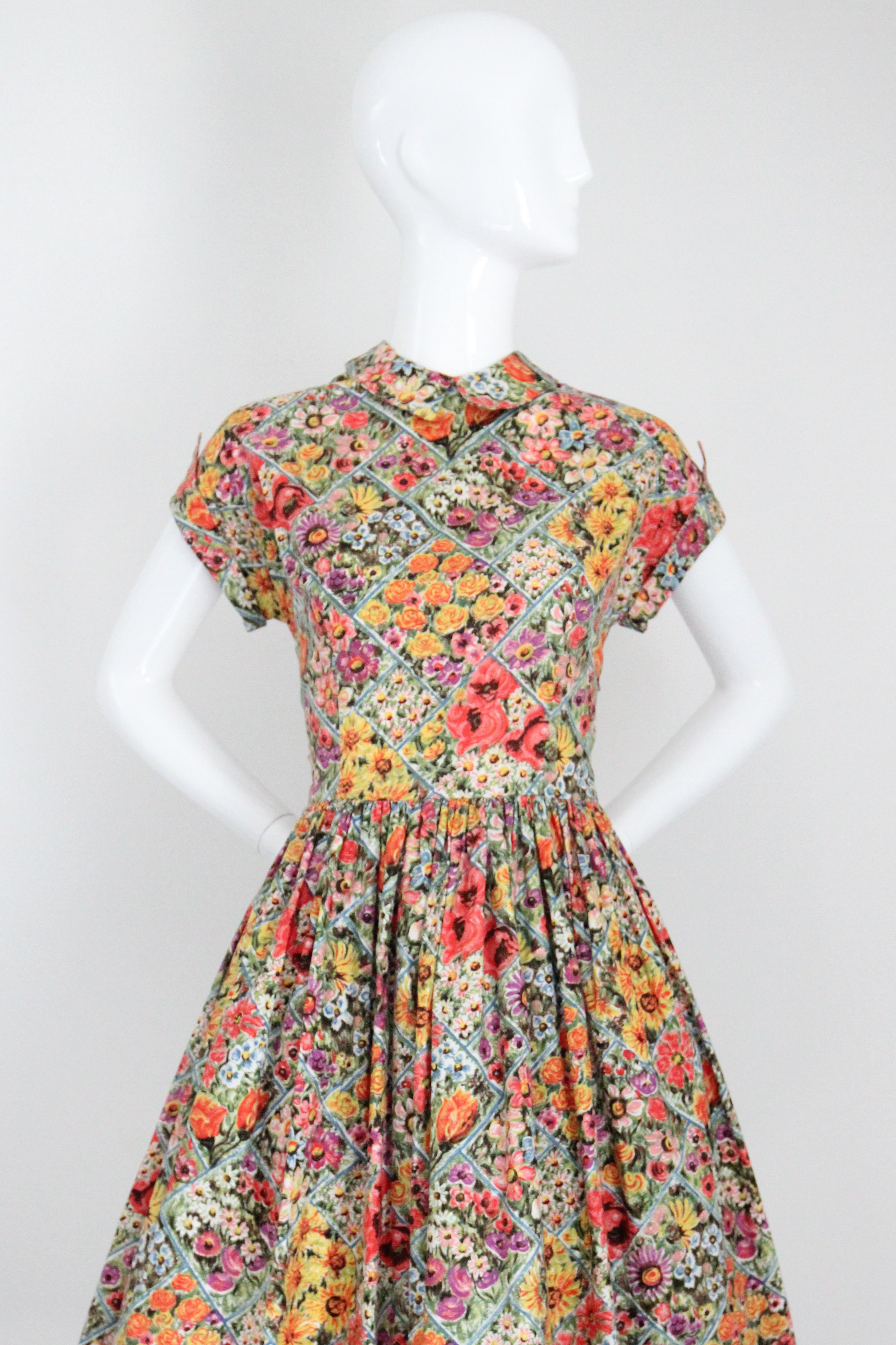 A true beauty of her time, this original 1950's cotton dress, with a pattern of wild flowers in shades of coral, pink, purple, yellow, white, and blue, surrounded with green foliage and a blue linear pattern, is just the piece to welcome the warmer