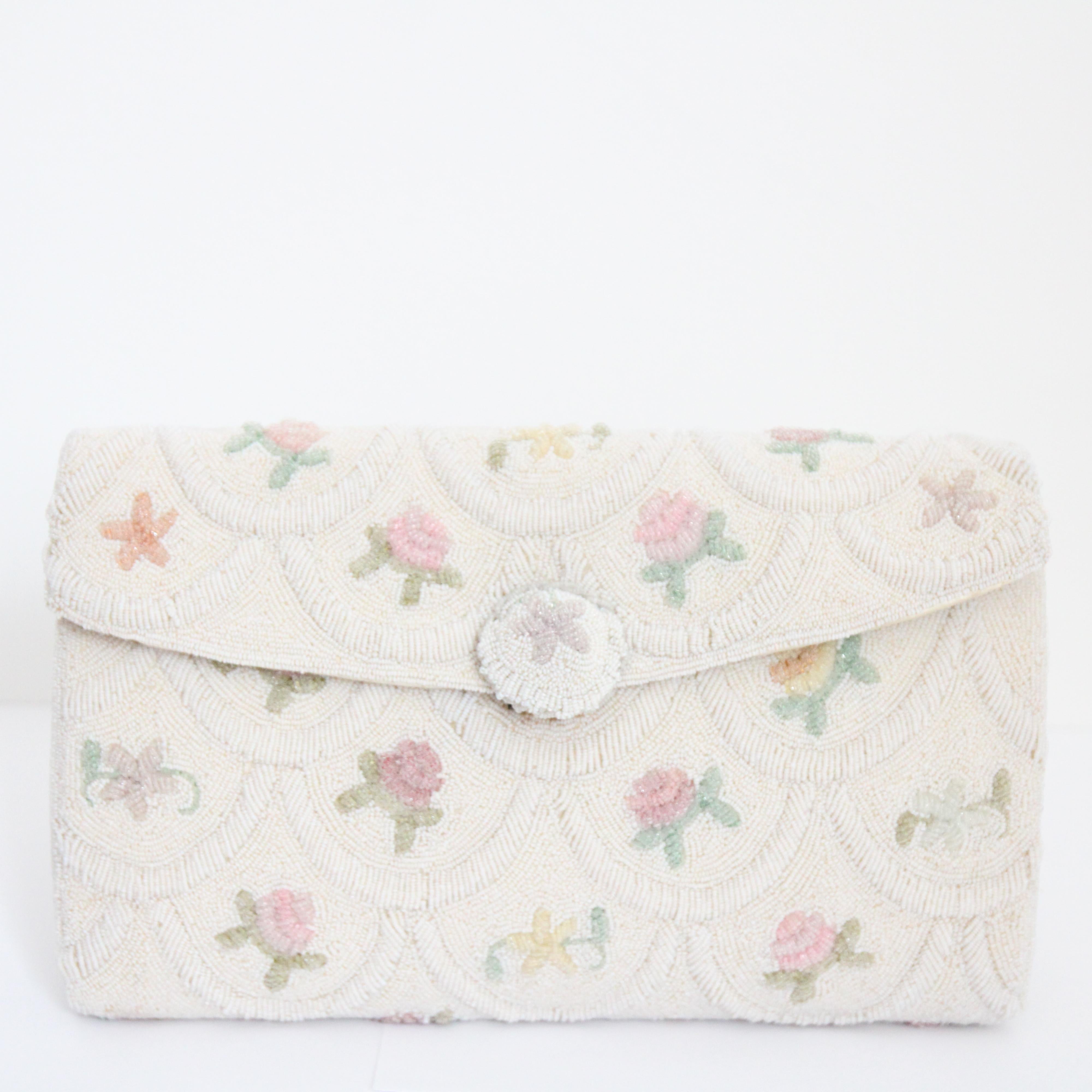 A true beauty to behold, this original 1950's micro beaded clutch bag, rendered in the smallest iridescent white rocaille beads, accented by a raised scalloped pattern throughout, in which the micro beaded floral patterns are positioned, in shades