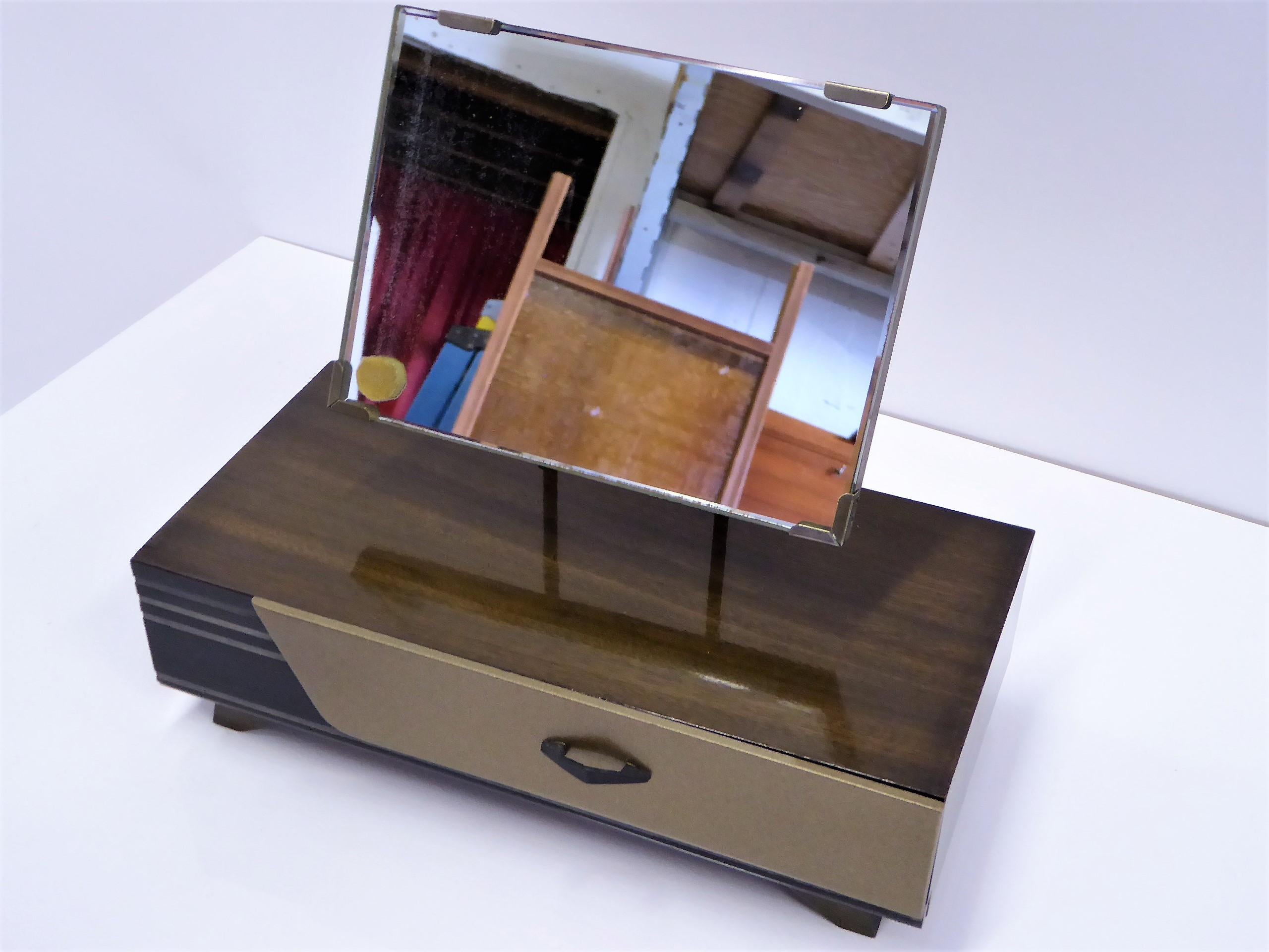 Beautiful petit table top Japanese Kyodai or makeup vanity cabinet with a mirror and drawer. With a 1950s streamline styling, it has a clear and black lacquer finish and a gold toned drawer front. The mirror which is adjustable, retains a gold foil