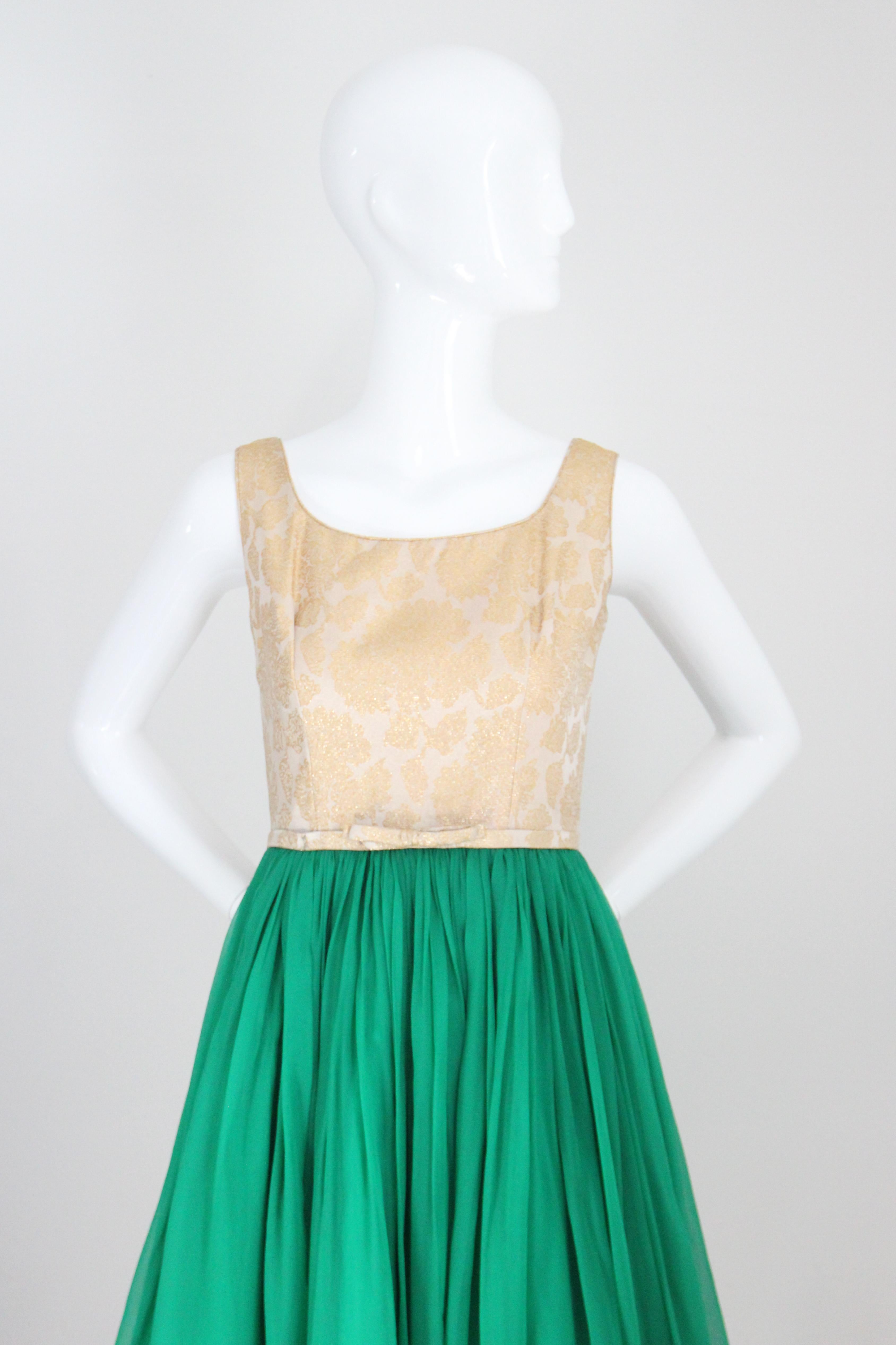 Rendered in the most eye-catching combination of gold silk and lurex floral brocade set against vibrant emerald green silk chiffon, this original 1950's cocktail dress is just the piece for that special occasion.  

The soft rounded neckline, is