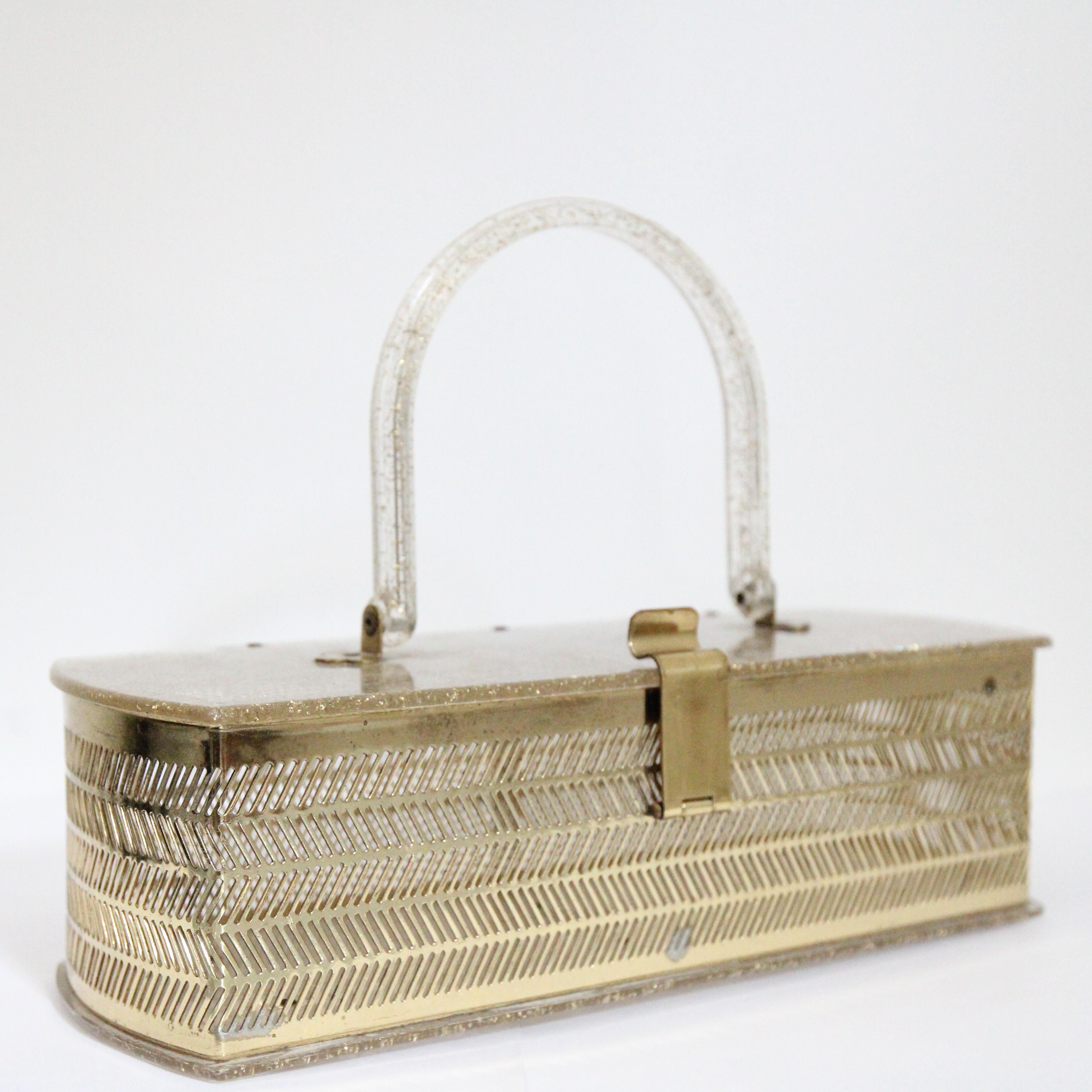 This breathtaking 1950's lucite and gold toned metal box bag, with the most interesting cut out design, is the perfect accessory for any vintage lover.

The rectangle shape of the bag showcases a gold toned cut out golden metal decorative body in a