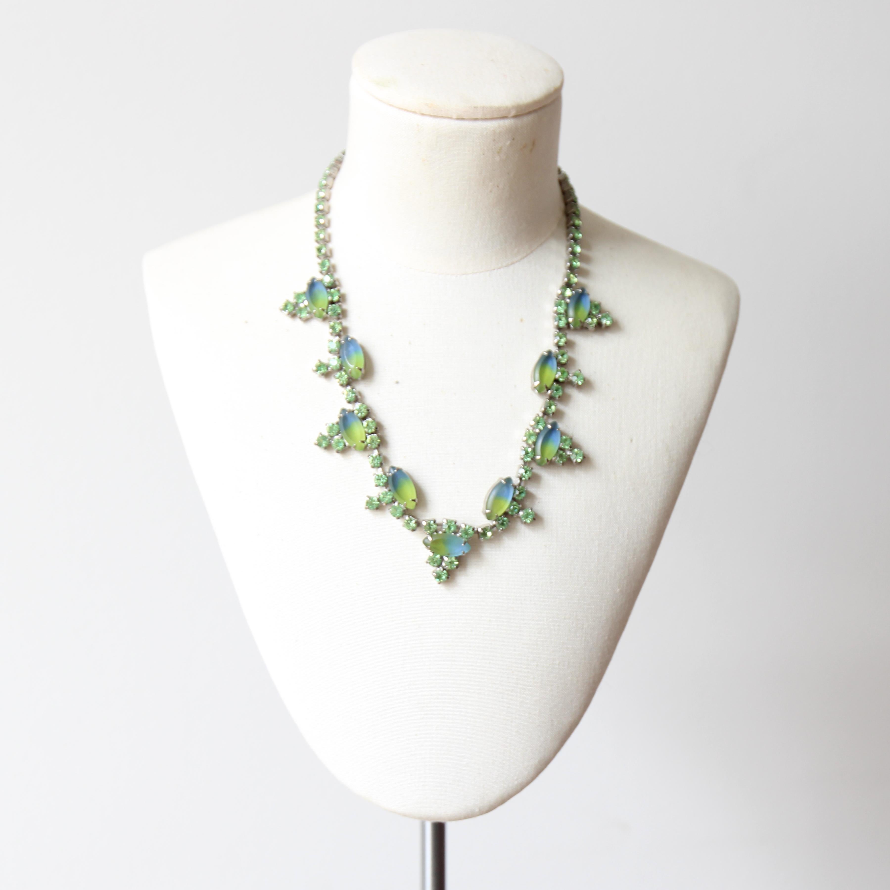 This elegant 1950's necklace, made up of mint green claw set rhinestones and petal shaped blue and green glass cabochons, is the perfect finishing touch to any outfit.

The decorative rhinestone linked chain boasts an alternating petal and