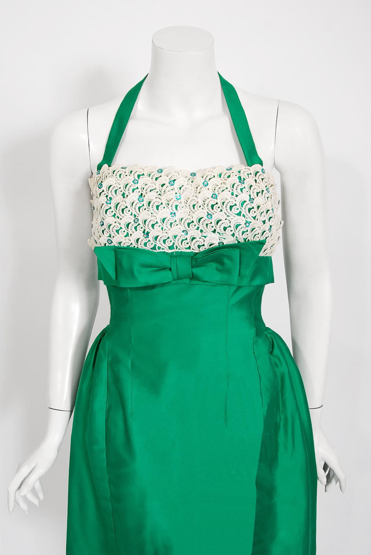 An amazing and highly stylized 1950's emerald green dress by the Lou-Ette California designer label. This gorgeous garment is fashioned from a luxurious polished cotton silk blend with white lace trimming. The silhouette is classic pin-up 