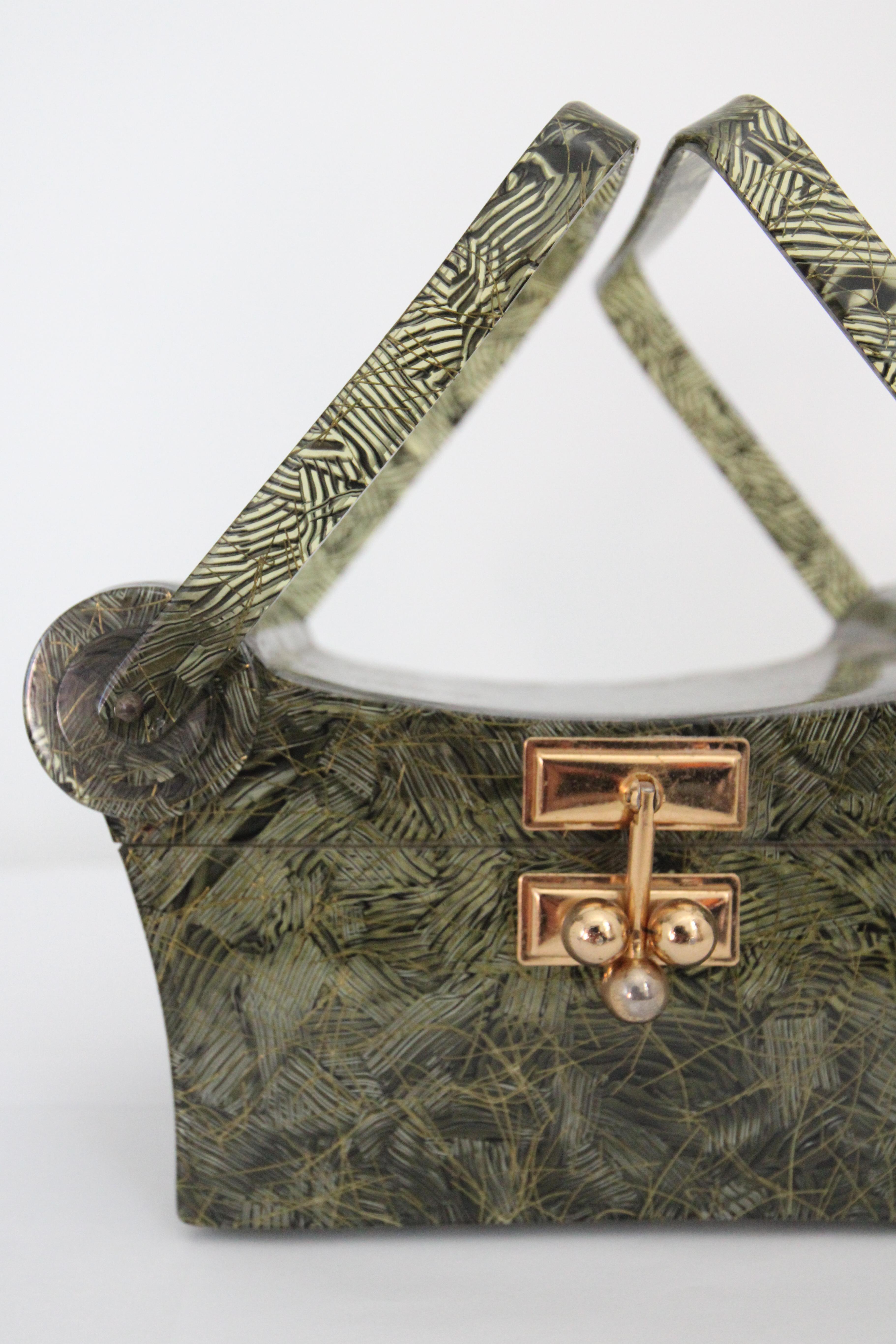 Rendered in the most interesting confetti pattern, in a deep shade of olive green with gold fleck accents, this original 1950's Myles Original of Miami lucite box bag, is a rare piece to behold. 

The elegant curved lid of the bag, is accented by