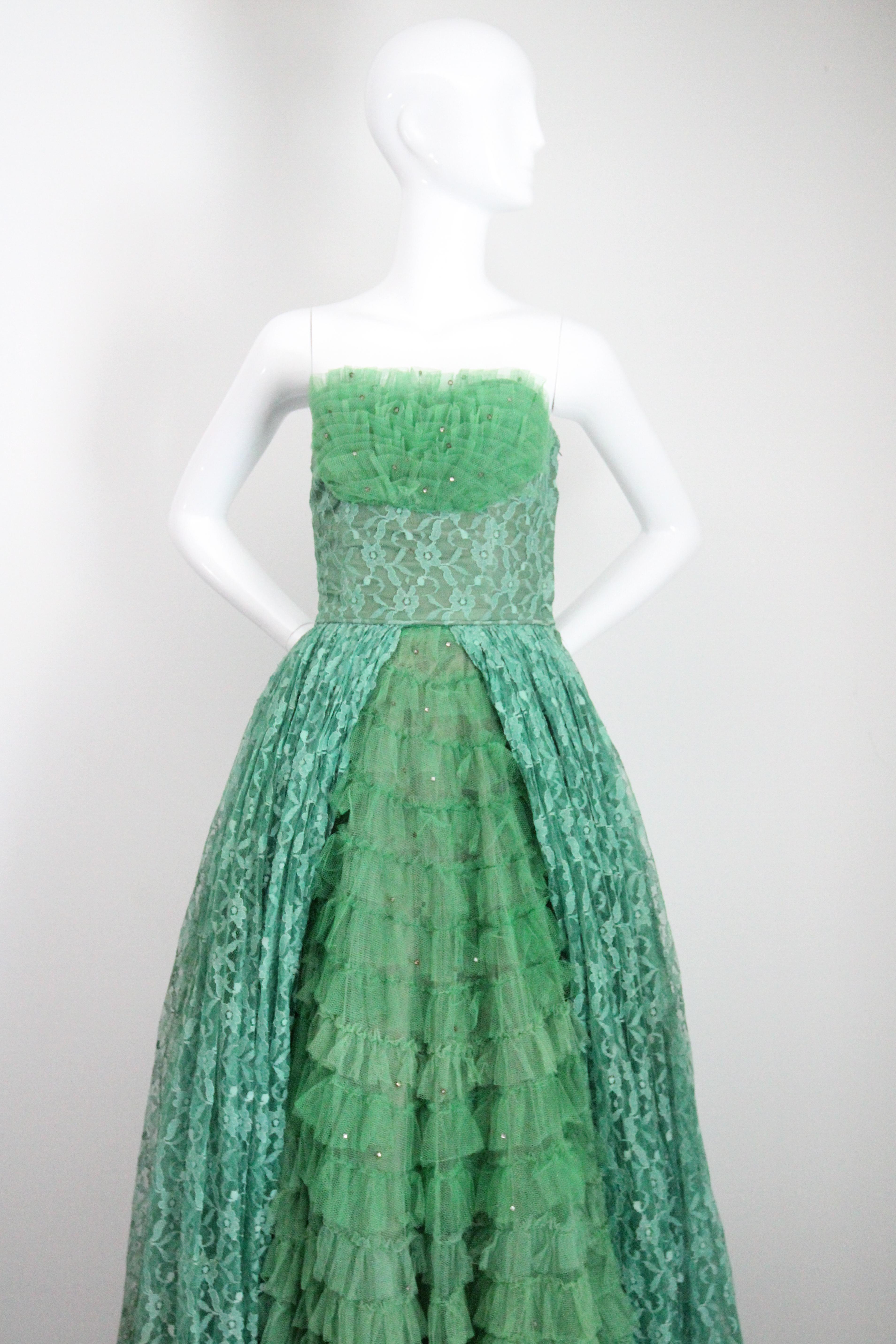 A phenomenal piece to behold, this original 1950's evening gown, rendered in forest green tulle, sea green lace and lined in fern green rayon, accented by delicate silver claw set rhinestones, is the perfect piece for that special occasion.

The