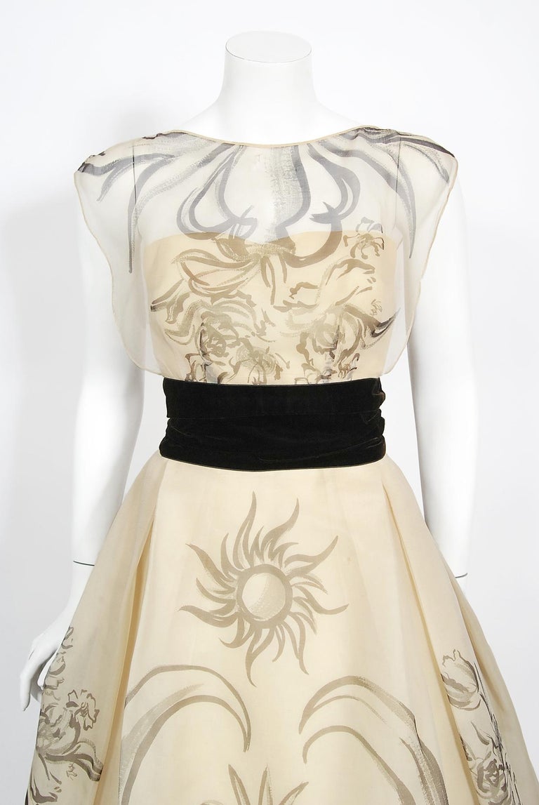 A breathtaking Hattie Carnegie couture whimsical hand-painted cream silk gown dating back to the early 1950's. Hattie Carnegie led a fashion empire that set the pace of American fashion for nearly three decades. She imported Paris designs, produced