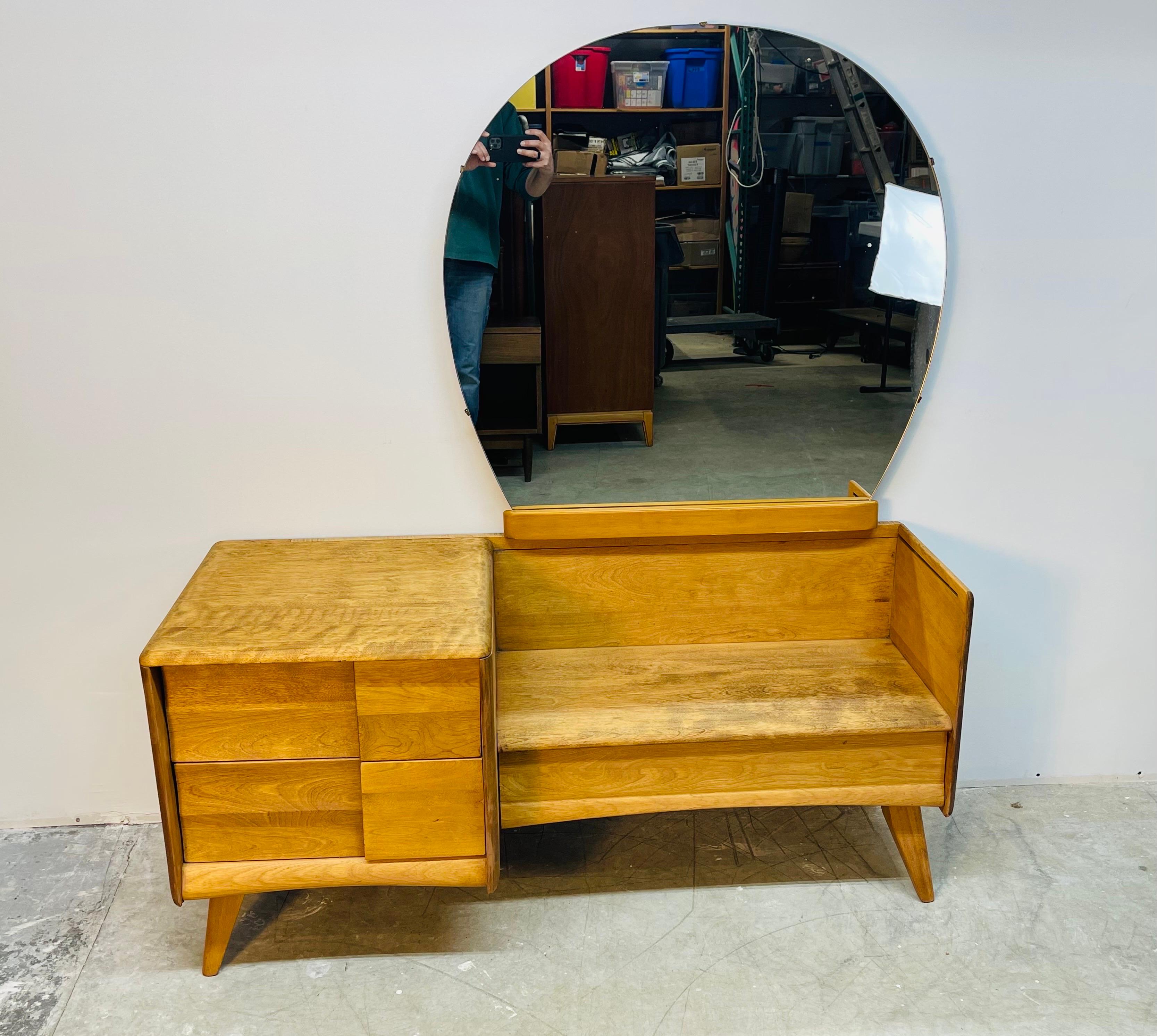 Vintage 1950s Heywood Wakefield maple wood vanity with round mirror. The vanity has been newly refinished and comes with three drawers for storage. The vanity is 23”H. With the mirror attached it is 55”H. And the seat height is 14.5”H. The mirror