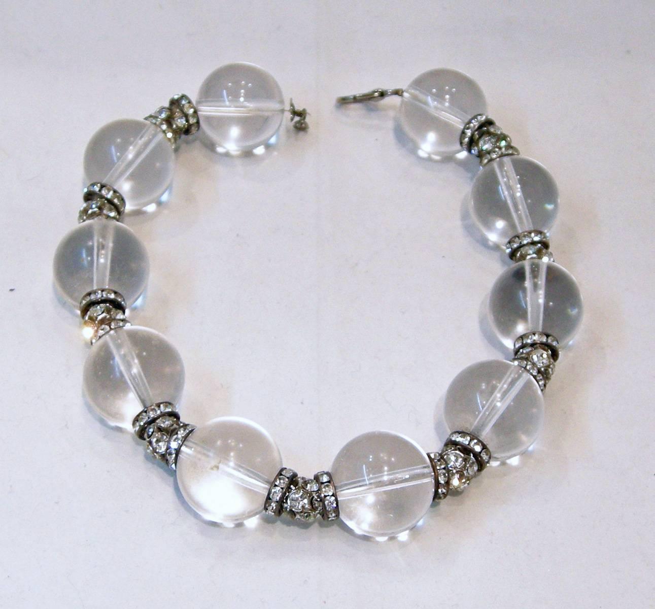 This Lucite necklace is right in style today.  It has huge round Lucite balls separated by rhinestone rhondells with rhinestone clusters in the middle.  It has a lobster clasp in a silver tone setting.  It measures 16-1/2” long and each ball is