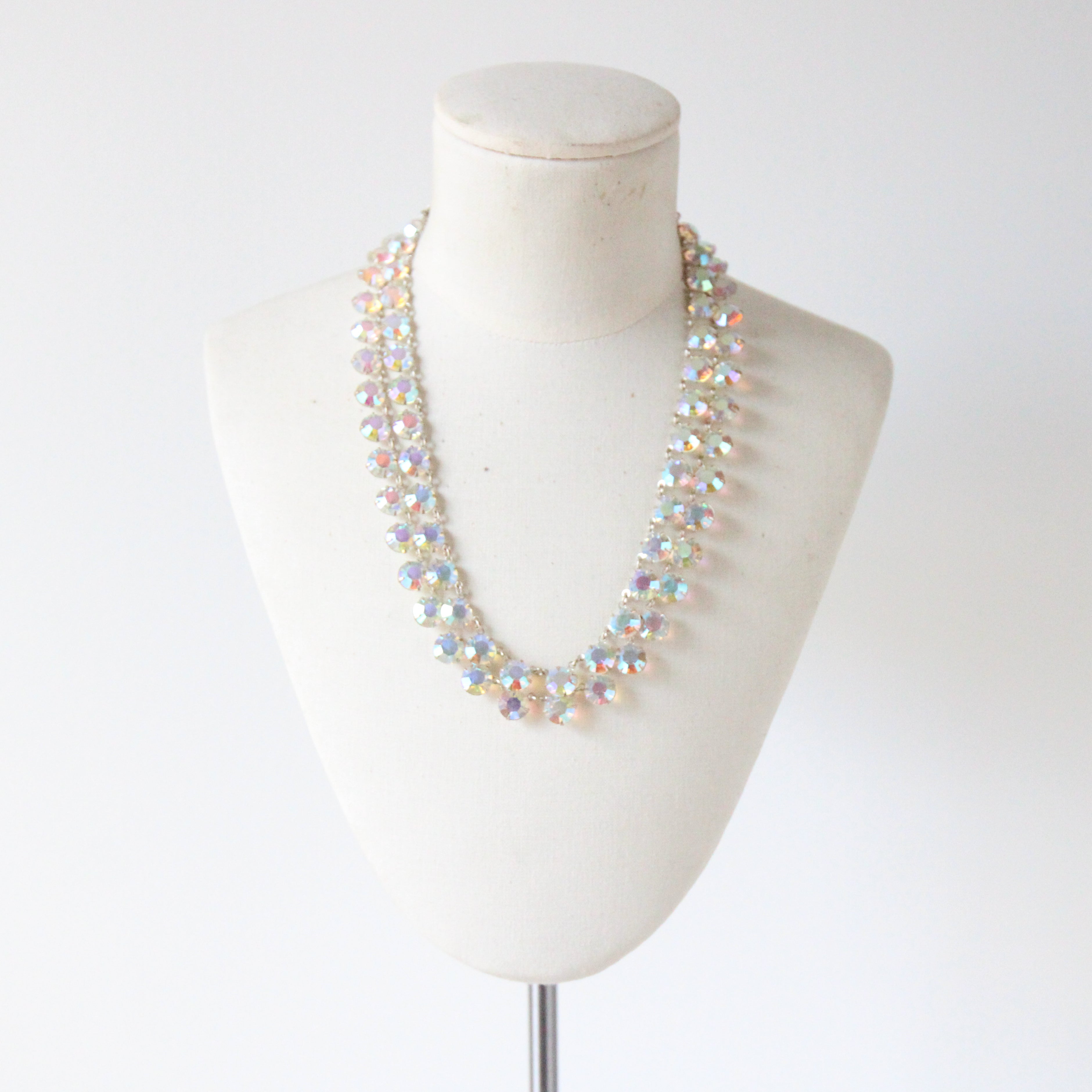 Questa scintillante collana di strass iridescenti degli anni '50, composta da due fili di strass incastonati, che si collegano con piccoli anelli d'argento e si uniscono alla parte posteriore della collana su due basi d'argento filigranato, è il