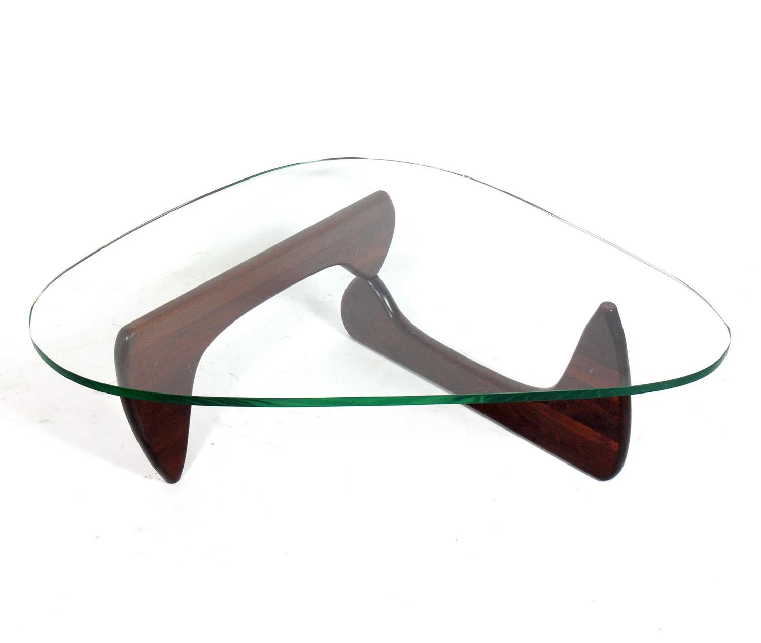 Sculptural coffee table, model IN-50, designed by Isamu Noguchi for Herman Miller, American, circa 1950s. The walnut base has been refinished and the table retains it's original green glass top.