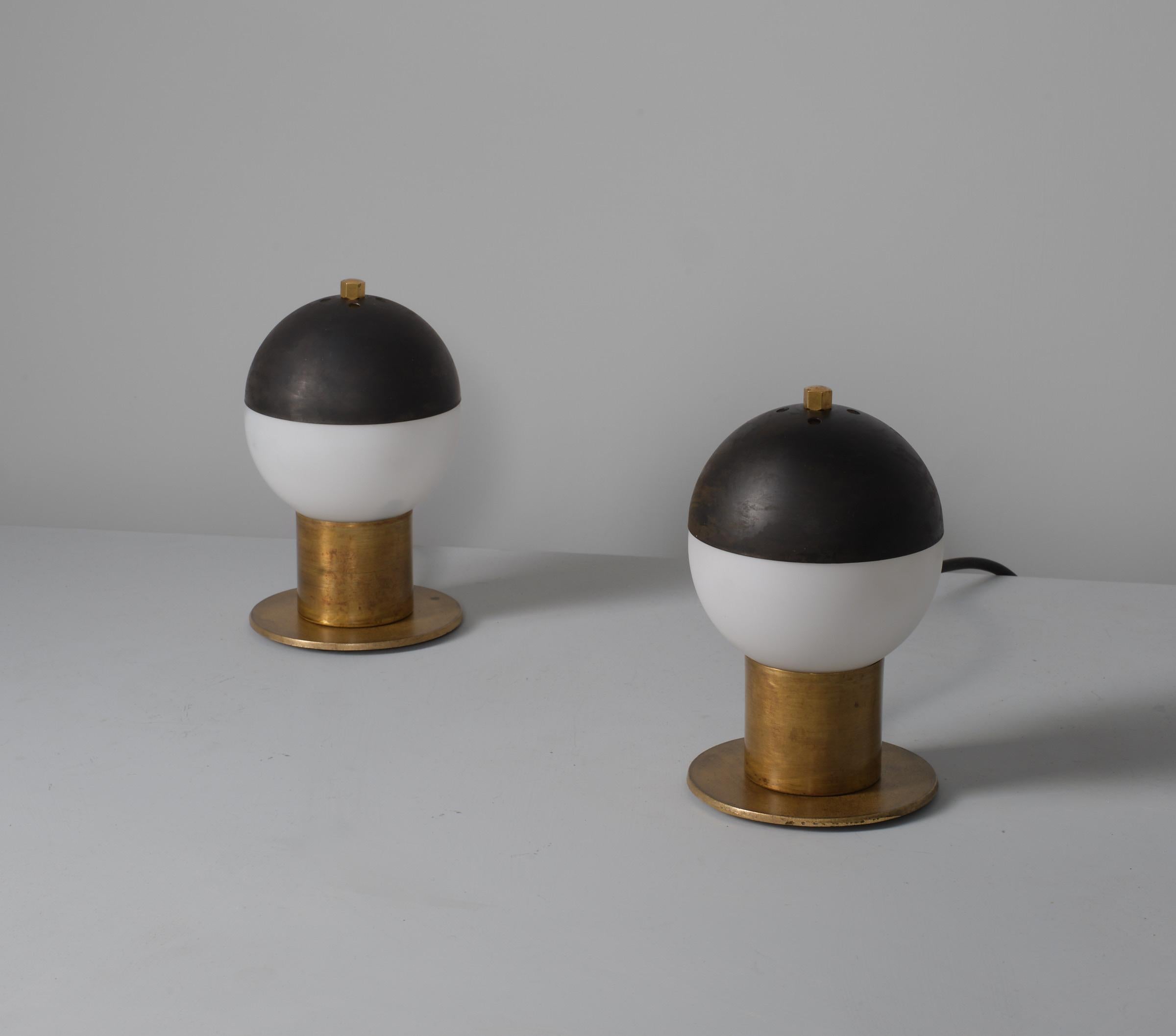 Discover the elegance of Italian design with this pair of brass table lamps from the 1950s, featuring striking blackened steel domes. The rich patina on the brass frames enhances the lamps' vintage appeal, while the sleek steel domes provide a