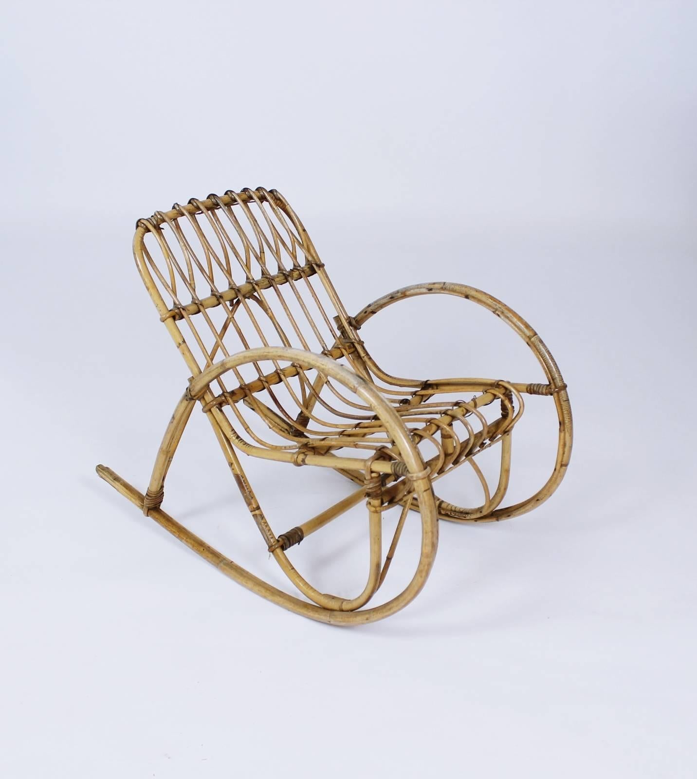 A vintage, circa 1950s, children's rocking chair in the bent rattan, graceful style of Franco Albini. Perfect for the little toddler or young child in your life. This chair is quite special in that its proportions are perfect and it is very