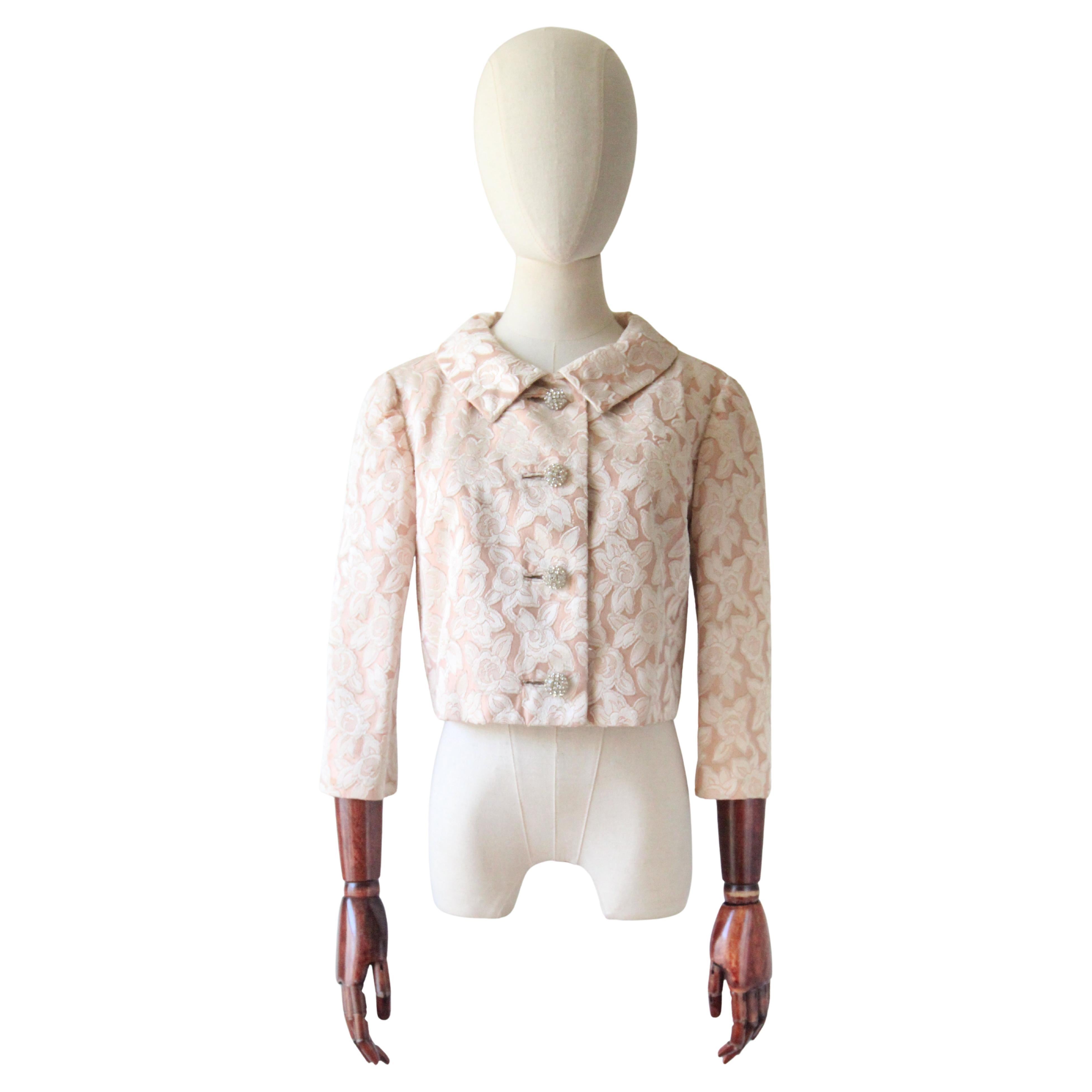 Realizzata in una silhouette classica, questa originale giacca in broccato di seta con stampa di rose degli anni '50, composta da uno sfondo di seta arrossata accentuato da rose di seta color crema, è un pezzo senza tempo da aggiungere alla tua