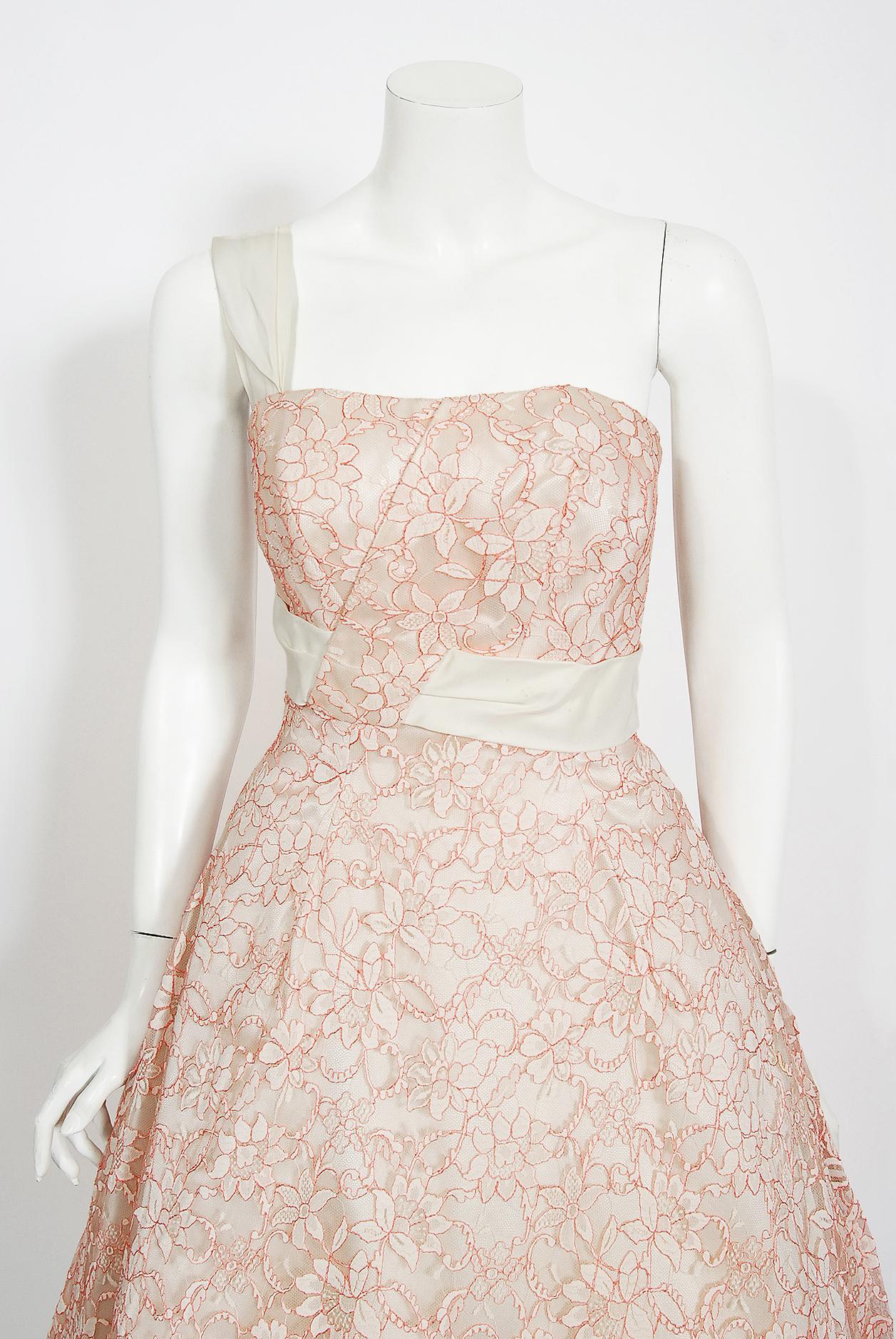 Romantic mid-1950's white and rose-pink sculpted full skirted party dress by a great French couturier, Jacques Heim. The entire garment is fashioned from the highest quality floral pattern Chantilly-lace. The interior, complete with corset boning