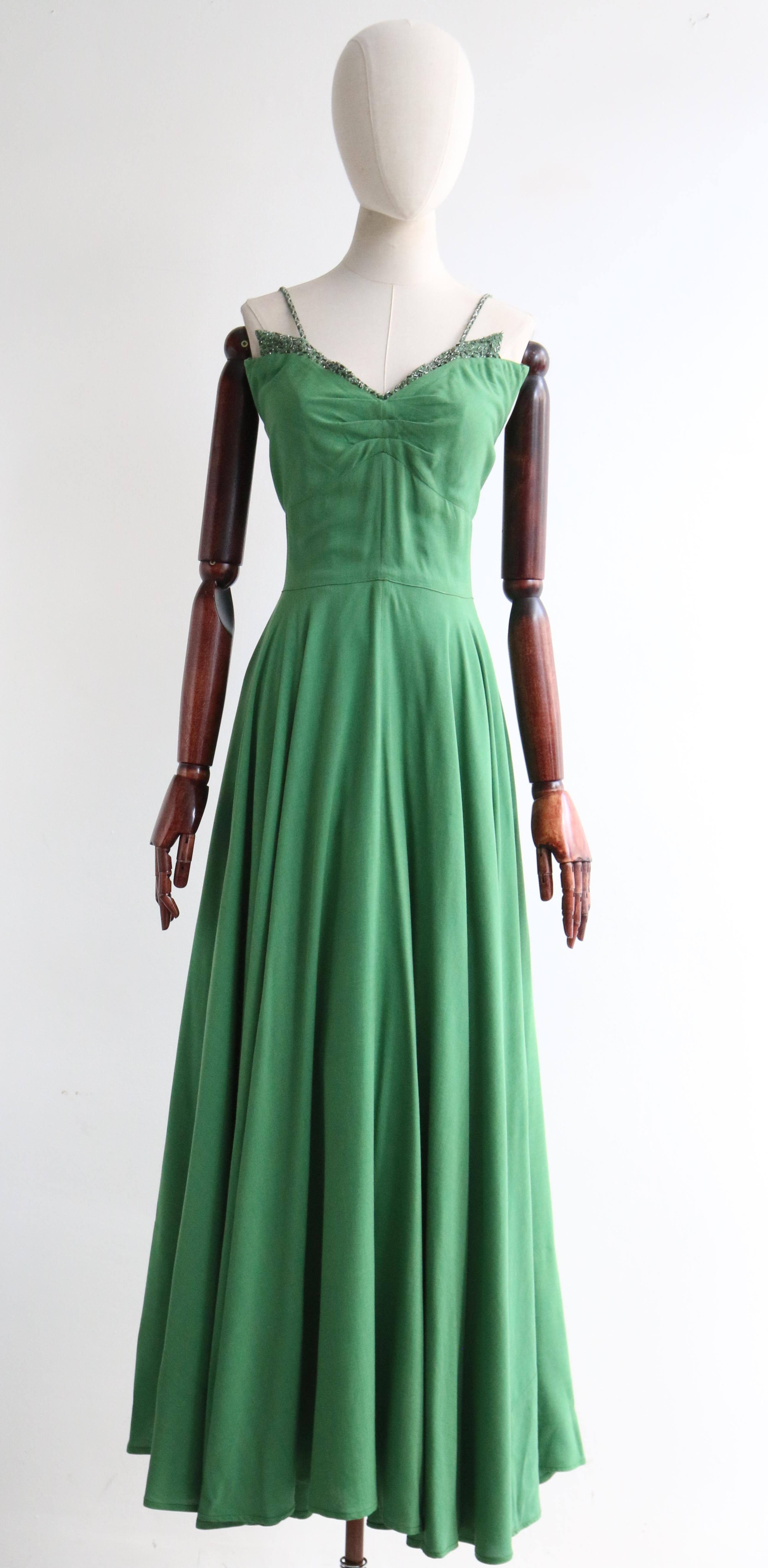 Made in the most delicious shade of jade green cotton and decorated with silver glass lined beads and gunmetal silver bugle beads, this original 1950's evening dress and matching bolero is just the perfect ensemble for that special occasion. 

The V