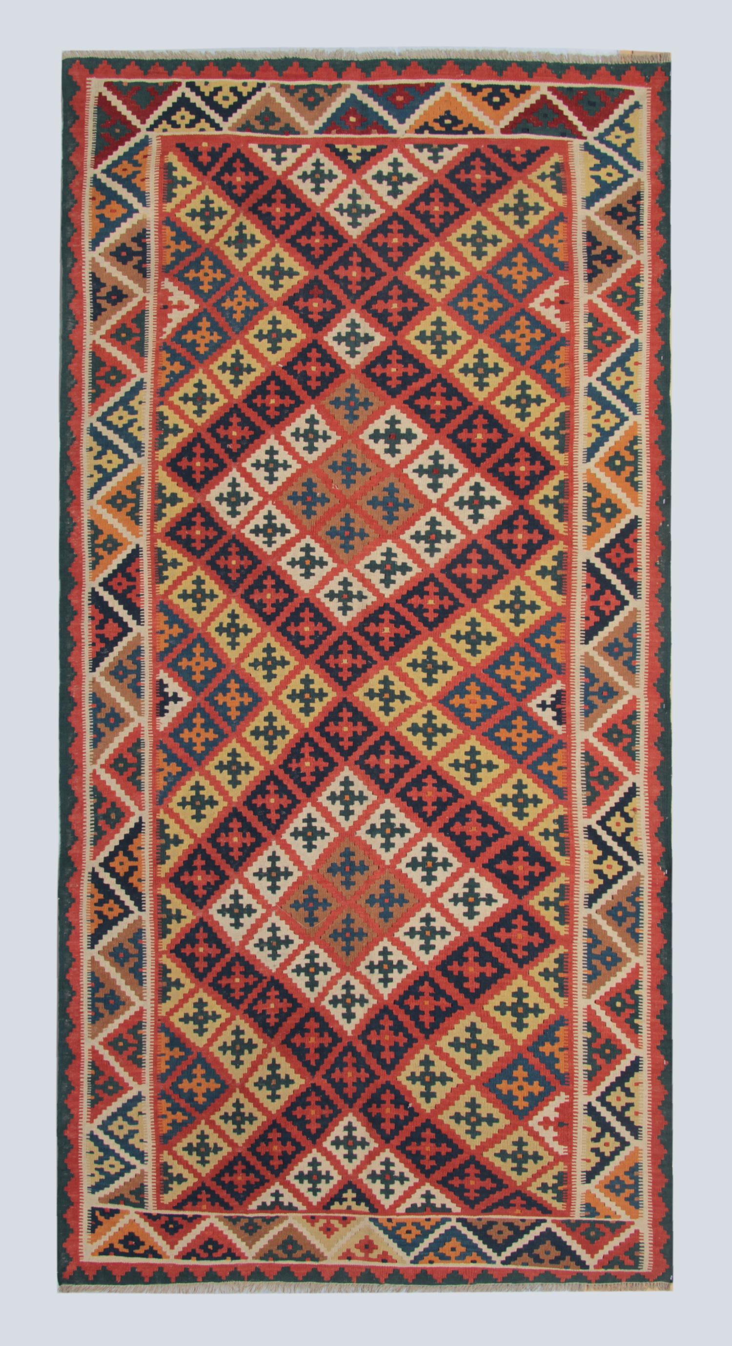 This 1950s vintage Kilim is an outstanding example of Central Asian tribal flatweaving, featuring a vibrant all-over arrangement of multicolour diamond motifs. Handwoven entirely in wool, the rug displays a lively palette of red, orange, green,