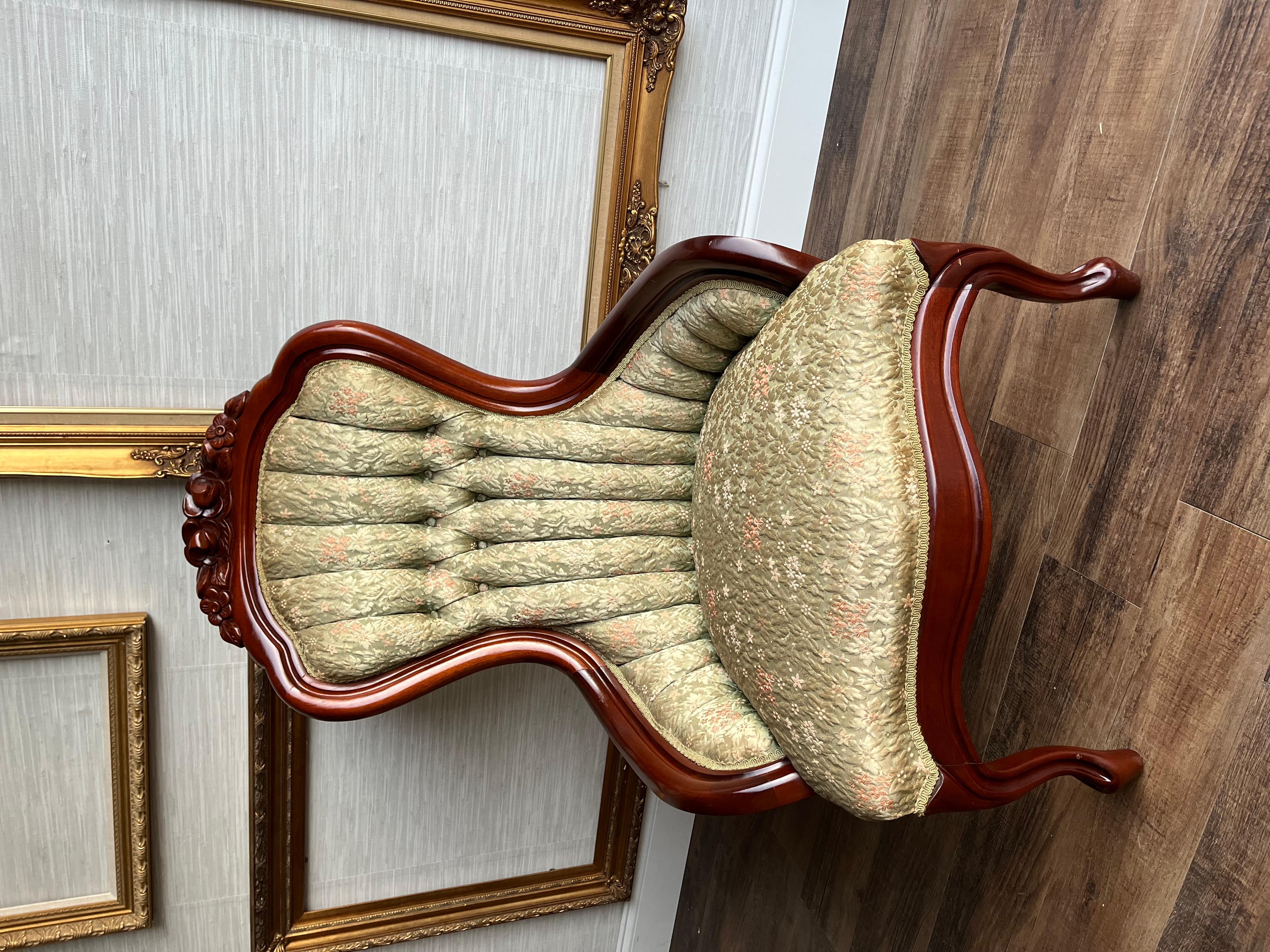 Immerse yourself in the timeless elegance of this Kimball Victorian Ladies' Parlor Chair, crafted in the 1950s. The frame is made from rich mahogany wood, exquisitely carved with intricate floral motifs that showcase the artistry of the period. The