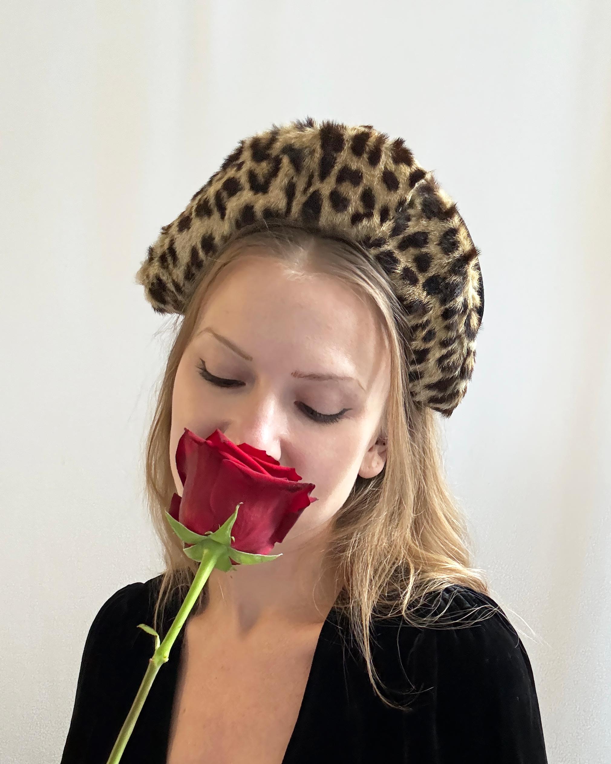 This 1950s bandeau headband hat/fascinator is rendered in a lush leopard print faux-fur. Crafted by hand and likely one-of-a-kind, its façade is angled backward and grows in height towards the crown of the head, creating an extremely face-flattering