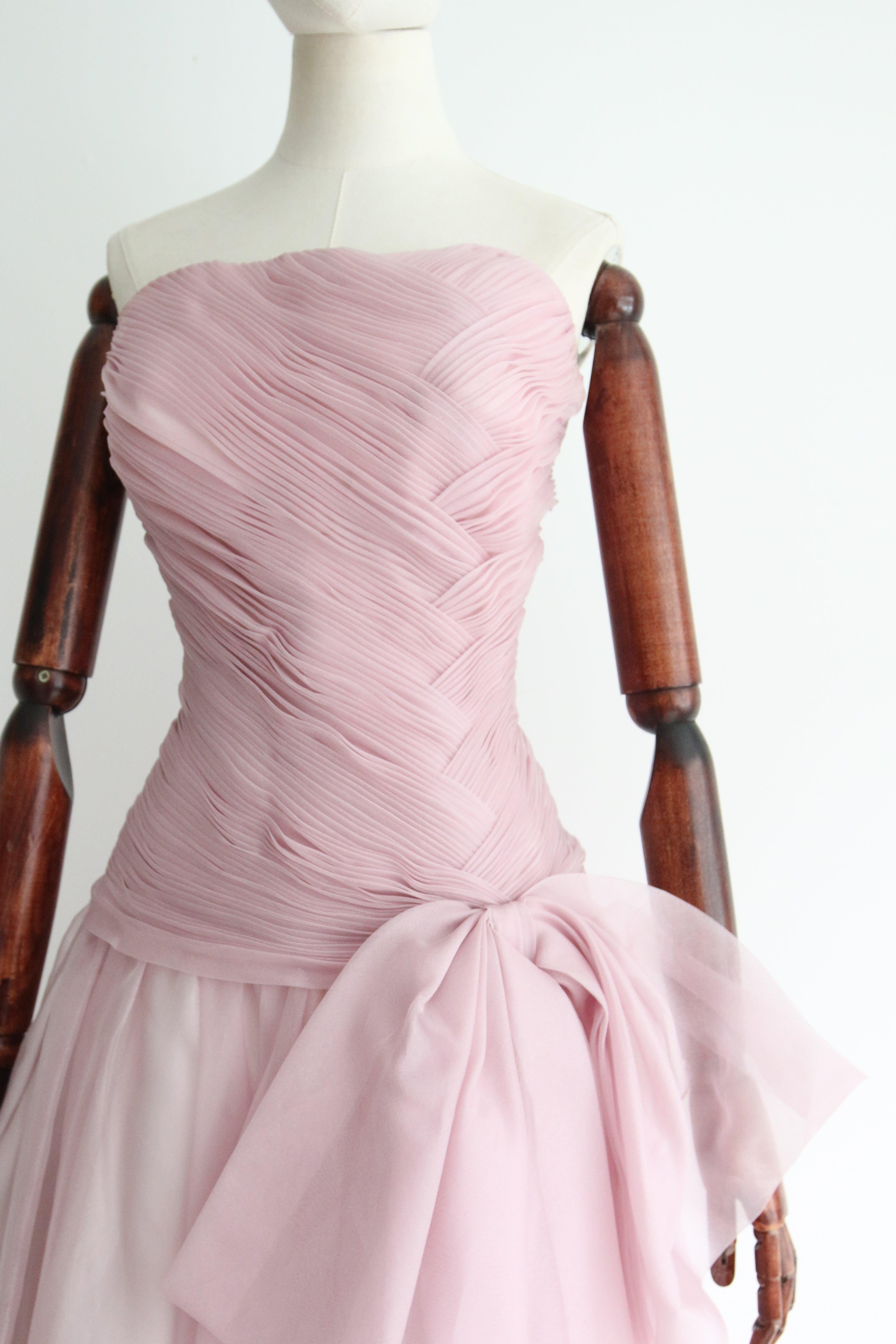 Rendered in the most breathtaking lilac coloured silk organza and accented by decadent pleats and a large statement bow, this original 1950's evening gown is a true piece of fashion history.  

The strapless cut of the dress is accented by a
