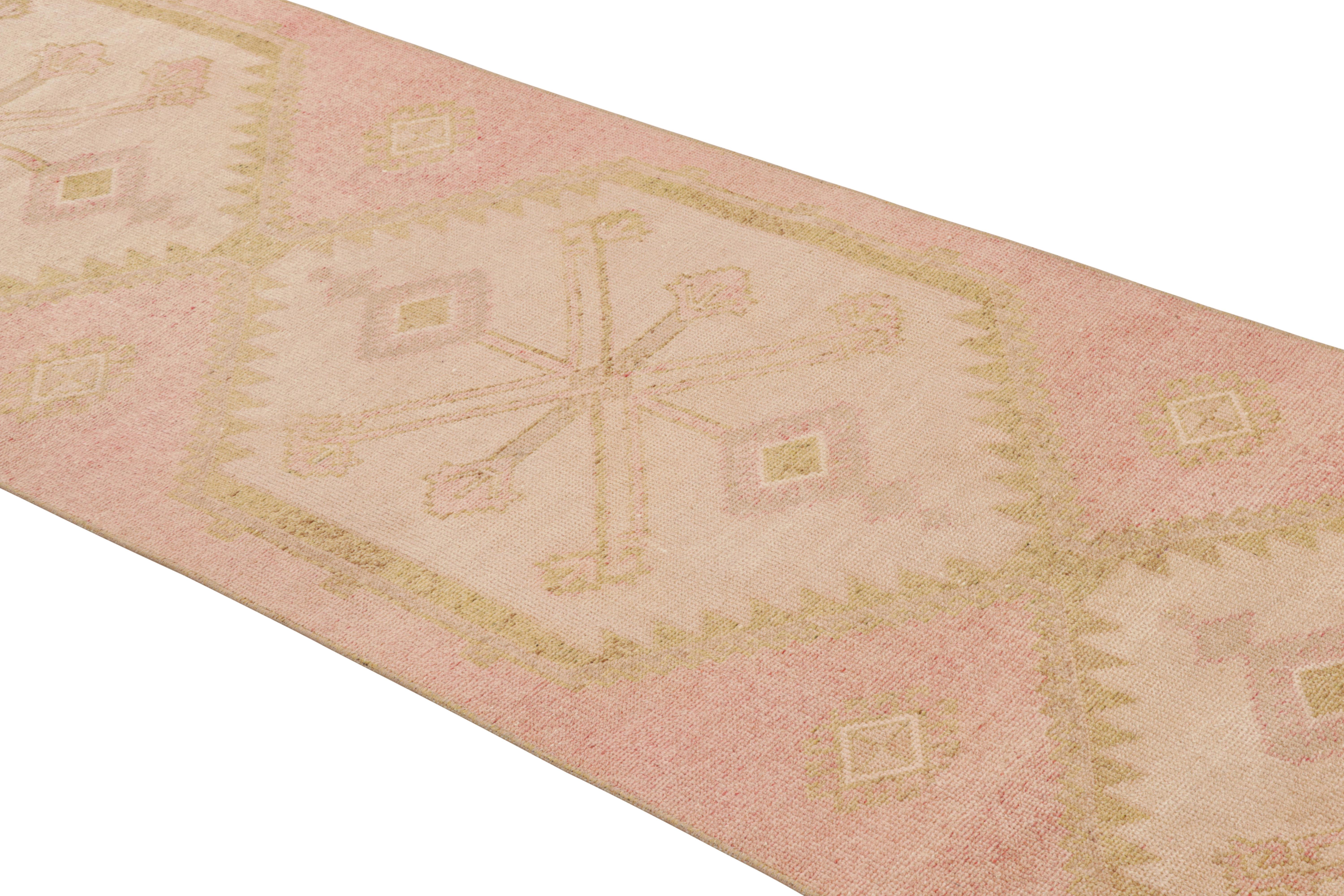 Made with handwoven wool originating from Turkey between 1950-1960, this vintage midcentury Kilim runner enjoys the distinction and gentility of a seldom-seen pink colorway, gracefully accented by a play of golden-beige and cream hues lending a
