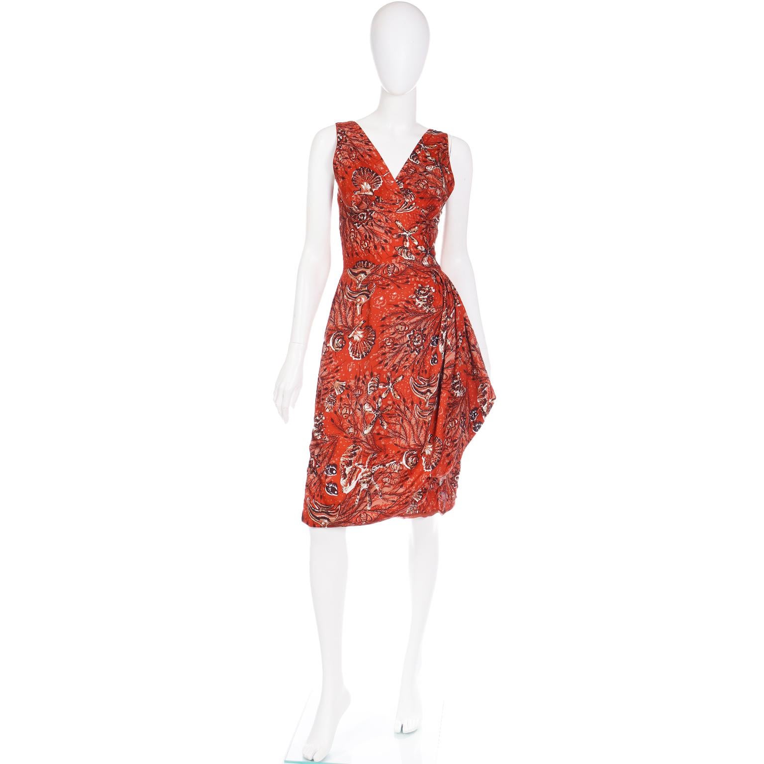 Dieser Spaß Vintage 1950's Sarong Stil Baumwollkleid ist in einem Spaß rostig Kupfer tropischen Ozean drucken.  Das Kleid hat einen tiefen V-Ausschnitt und schöne Raffungen an der Seite, die einen asymmetrischen Faltenwurf erzeugen. Es gibt einen 5