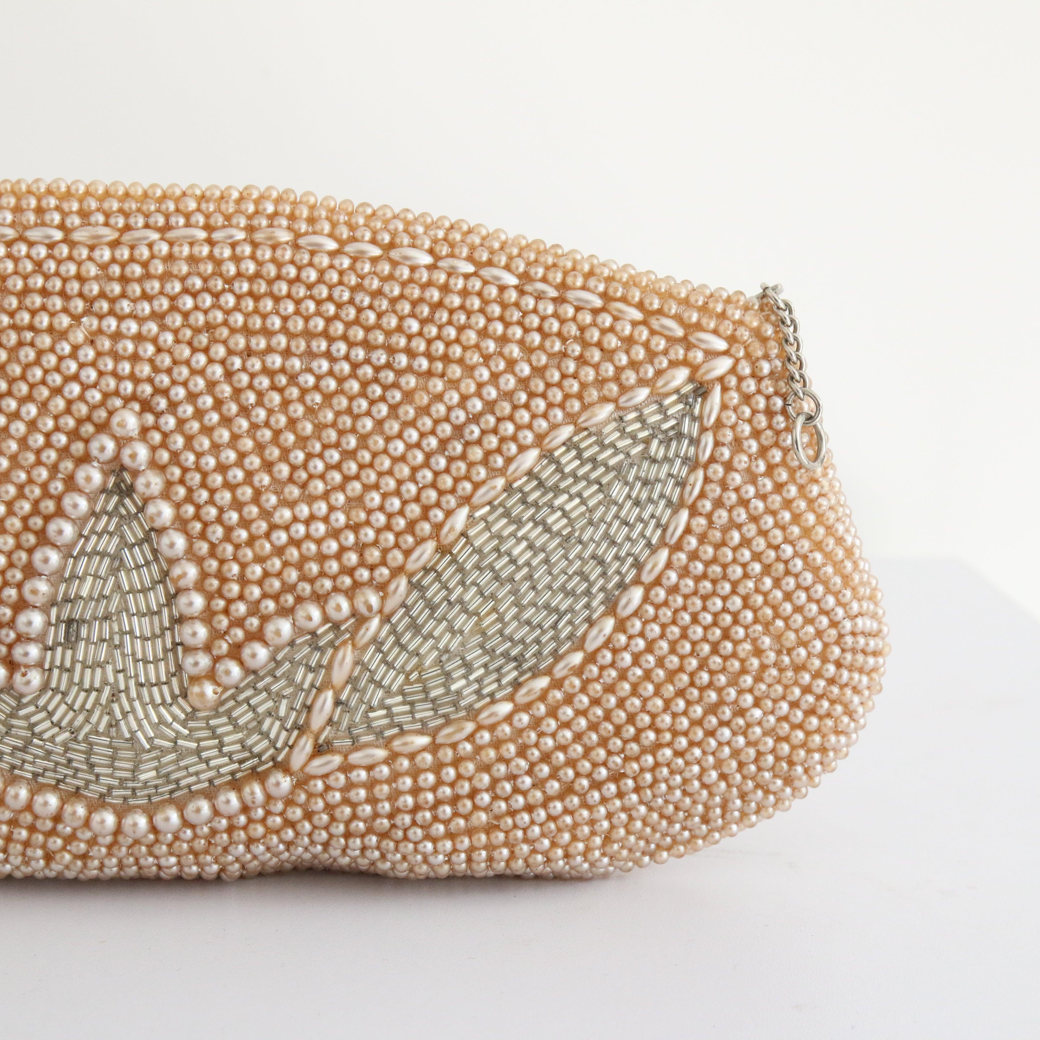 This wonderful 1950's beaded clutch bag, embellished with champagne pearlised plastic beads and gun metal grey glass bugle beads in a botanical design, is the perfect finishing touch to your outfit. The rounded rectangle shape of the bag  frames 