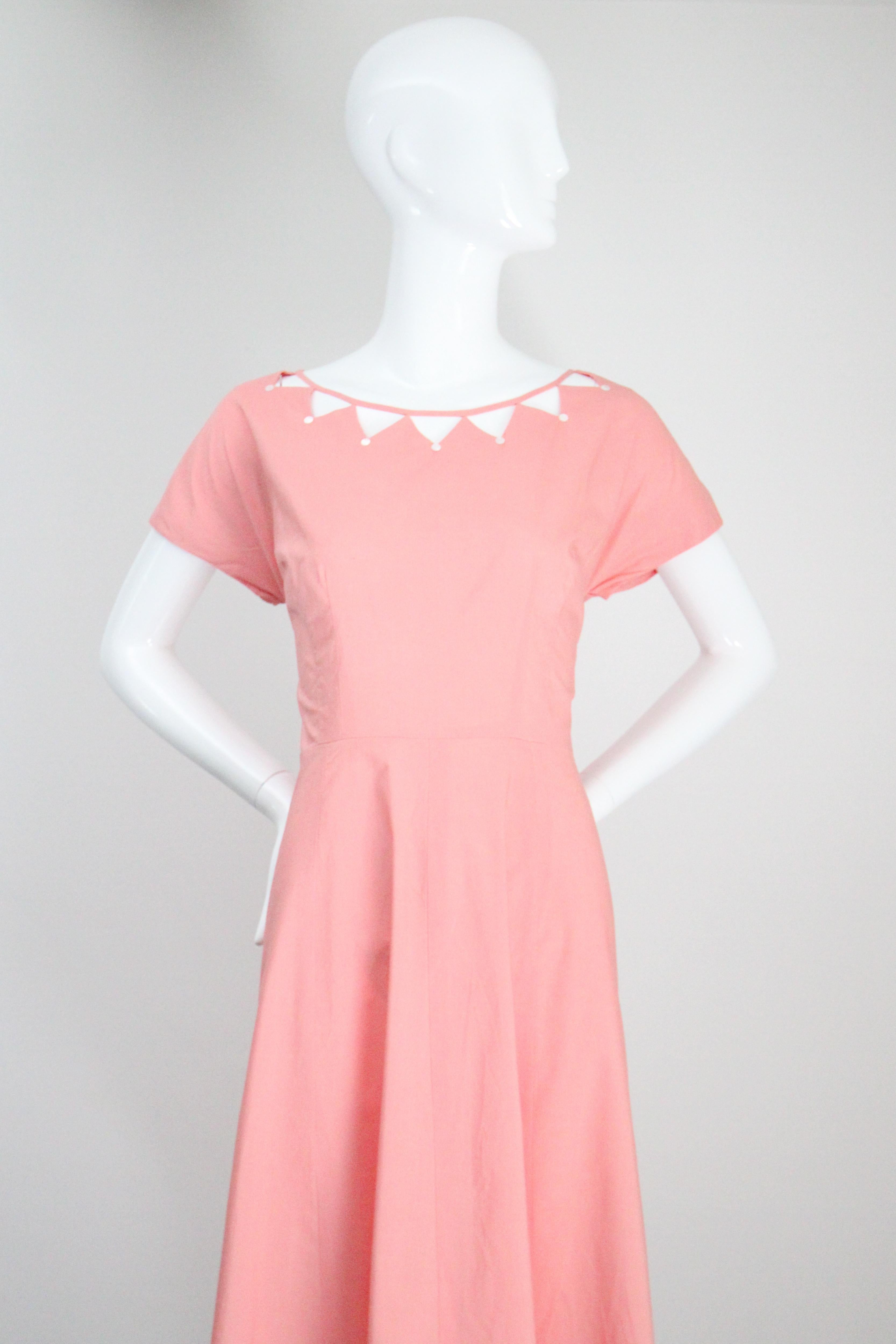 Réalisée dans la nuance la plus douce de coton rose et accentuée par une encolure décolletée, cette robe de jour originale des années 1950 est exactement la pièce qu'il vous faut pour accueillir les beaux jours. . 

L'encolure arrondie est rehaussée