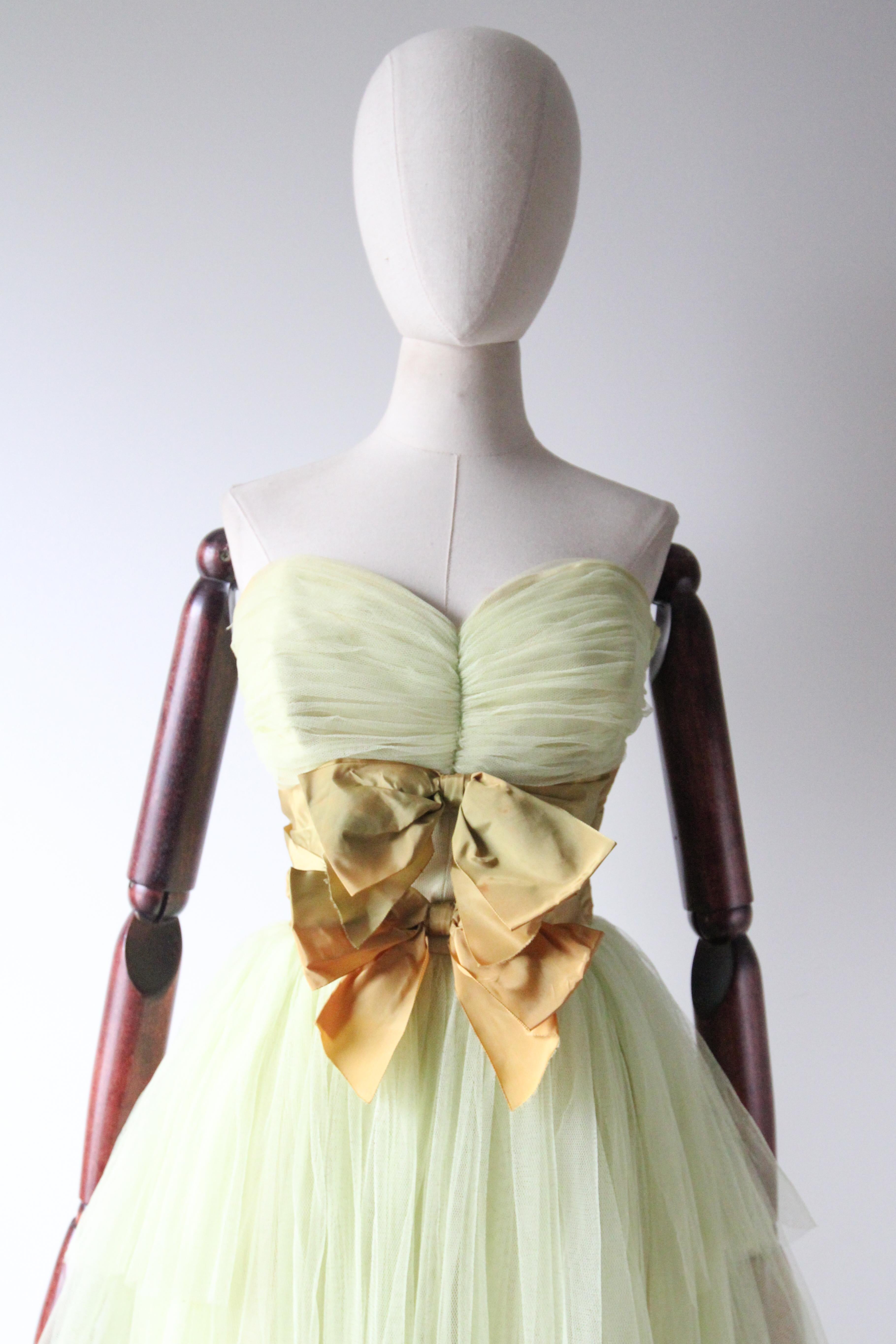 Rendered in the softest shade of pistachio coloured tulle and decorated with chartreuse green faille ribbon, this original 1950's tulle dress is the perfect piece for that special occasion. 

The sweetheart strapless neckline of the dress is