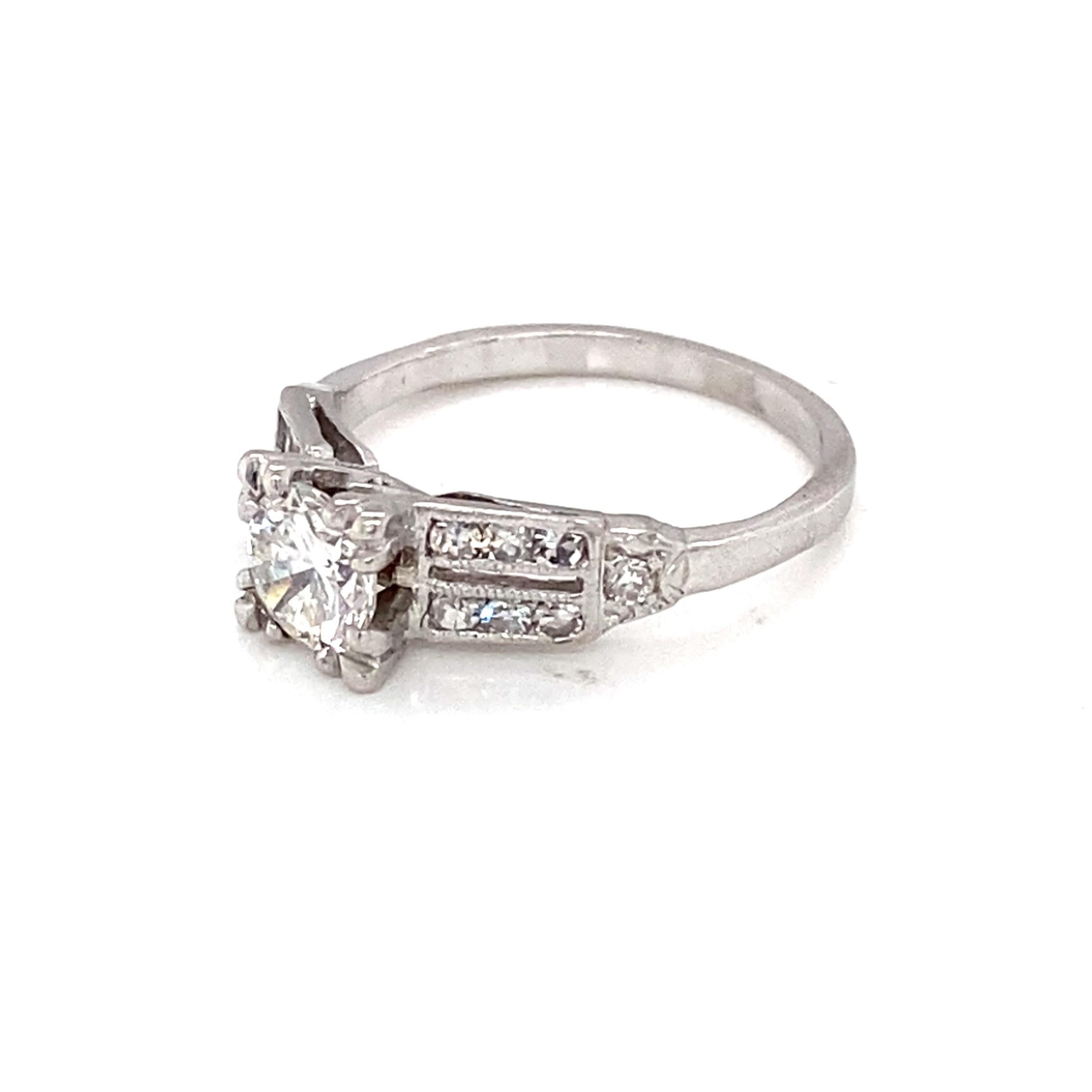 This delightful circa 1950s vintage platinum and diamond engagement ring features a center approximately 0.56 carat modern brilliant-cut diamond with G - H color grade and SI1 - SI2 clarity grade set into a four-prong split setting.  The shoulders