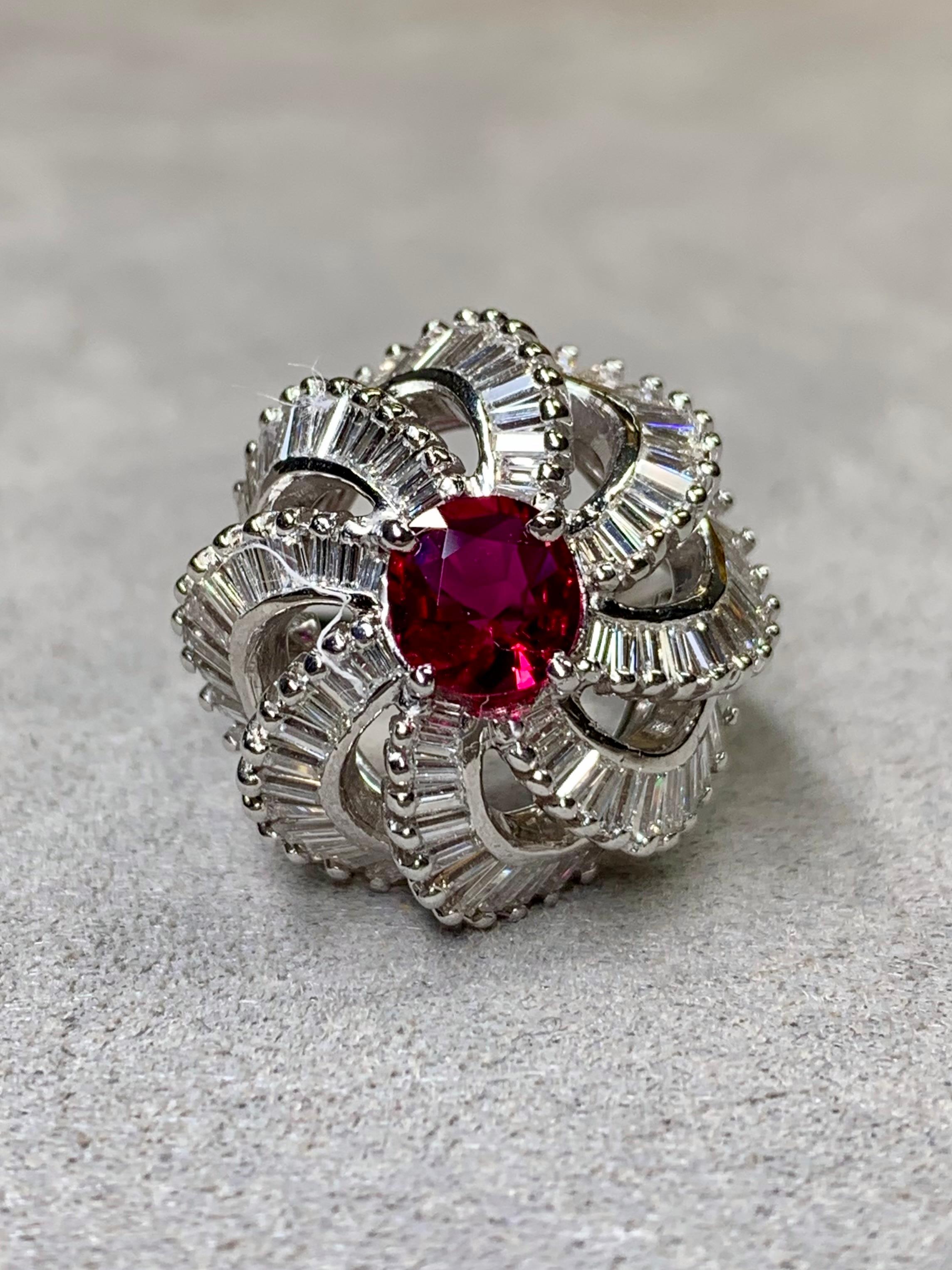 A fabulous cocktail ring c. the 1950’s done in platinum and set with approximately 4ctw in graduated G-I color Vs1+ clarity baguette diamonds in a domed spiral design. The ring is centered by a 1.03ct vivid red cushion cut natural ruby. The sale of