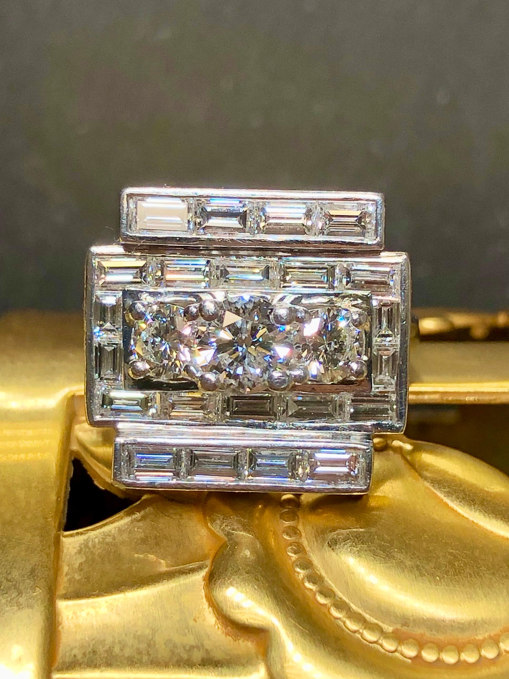 
A spectacularly gorgeous cocktail ring Circa the 1950s done and very heavy platinum and channel set with numerous large baguette cut diamonds ranging F-G in color and Vs1+ in clarity. Centering this ring are three larger round cut diamonds totaling
