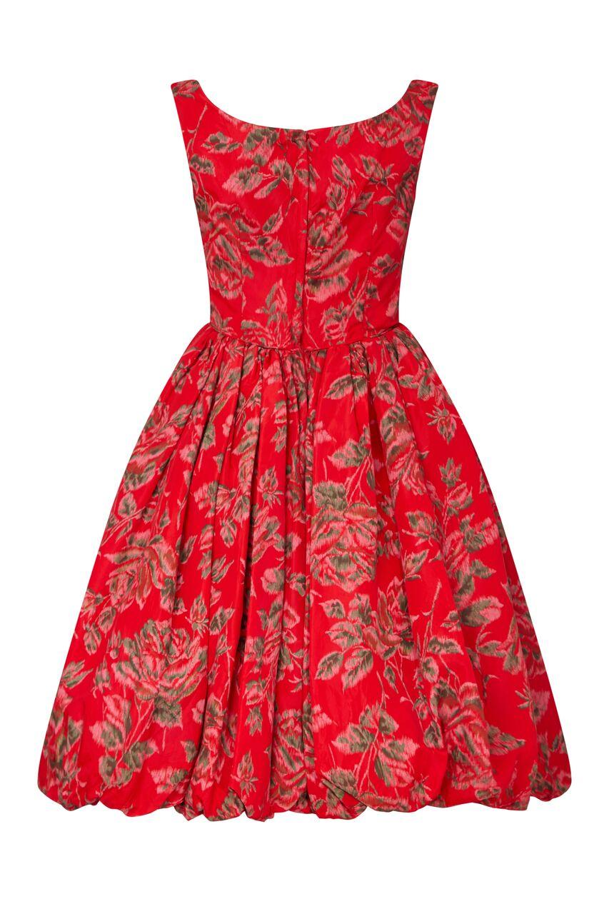 This arresting 1950s tulip party dress in red floral taffeta is in very good to excellent vintage condition and with a beautiful new look style silhouette. The gently abstracted rose design in dusky pink and olive green blends beautifully against