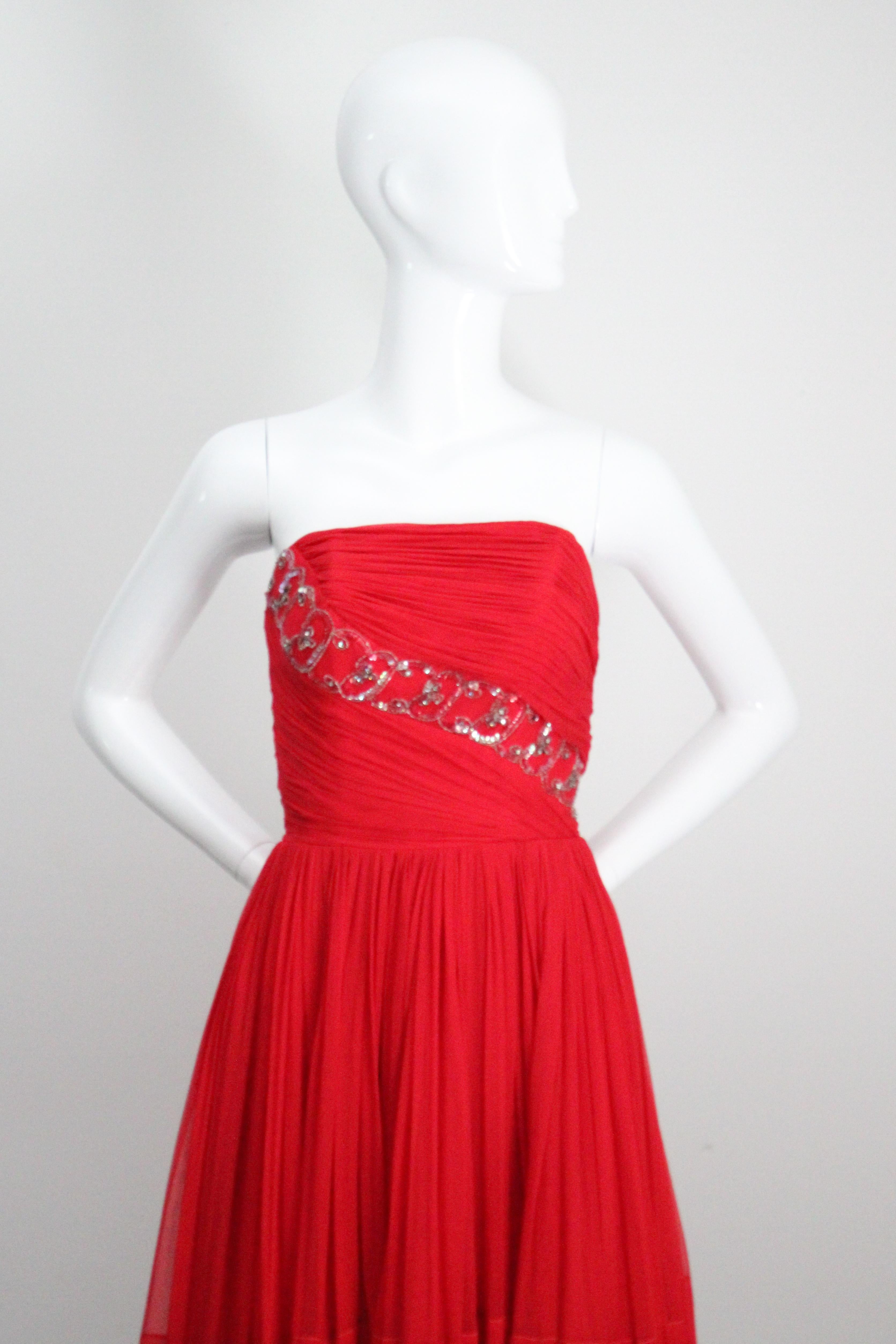 Rendered in the most eye-catching shade of red silk chiffon and embellished with silver lined glass bugle beads, red iridescent sequins and silver claw set rhinestones, this original 1950's cocktail dress is just the piece for that special occasion.