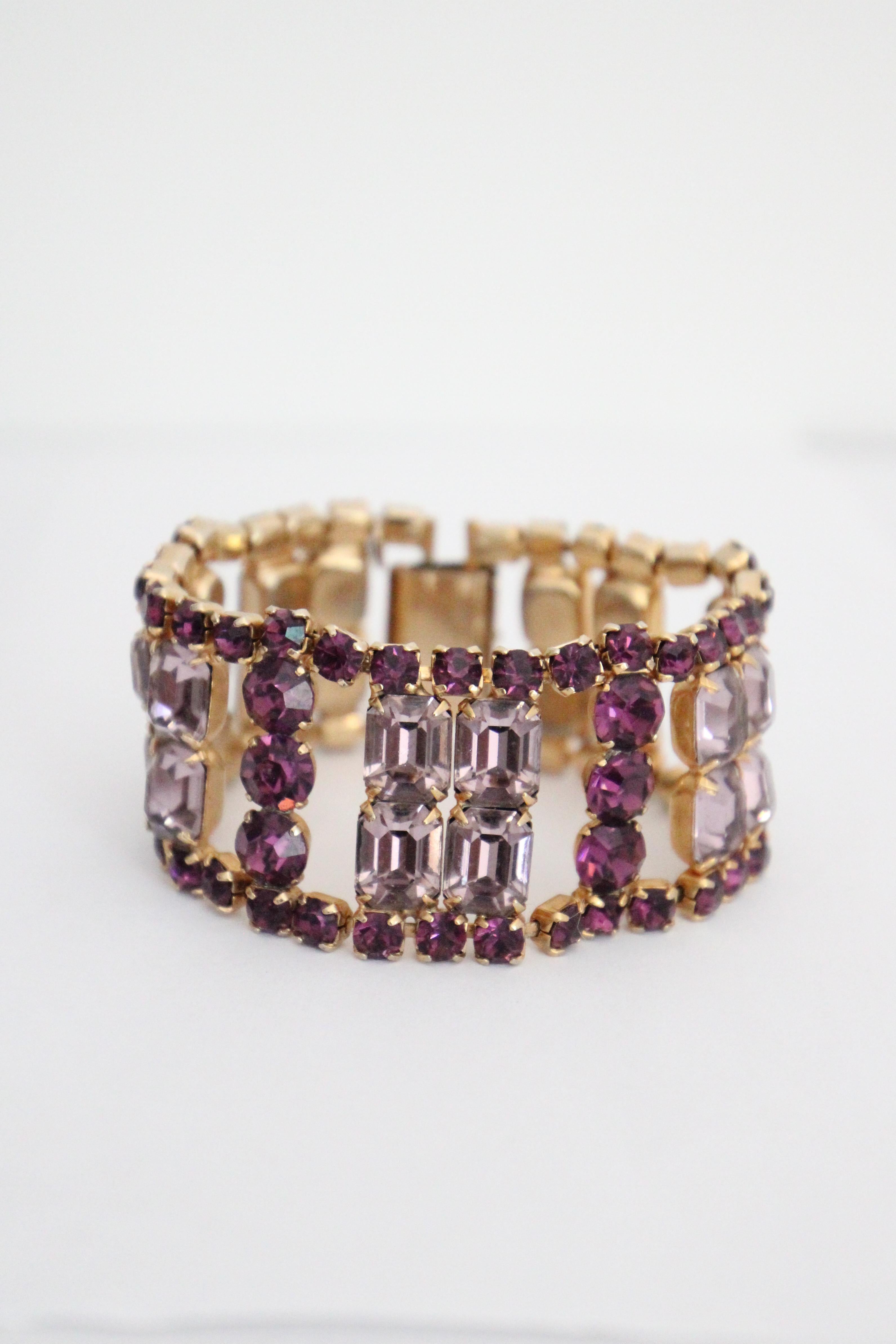 Ce spectaculaire bracelet en strass des années 1950, de couleur lilas et améthyste, monté sur une base en métal doré, est la touche finale parfaite pour votre tenue. La manchette du bracelet est ornée de strass de couleur améthyste sur chaque bord,