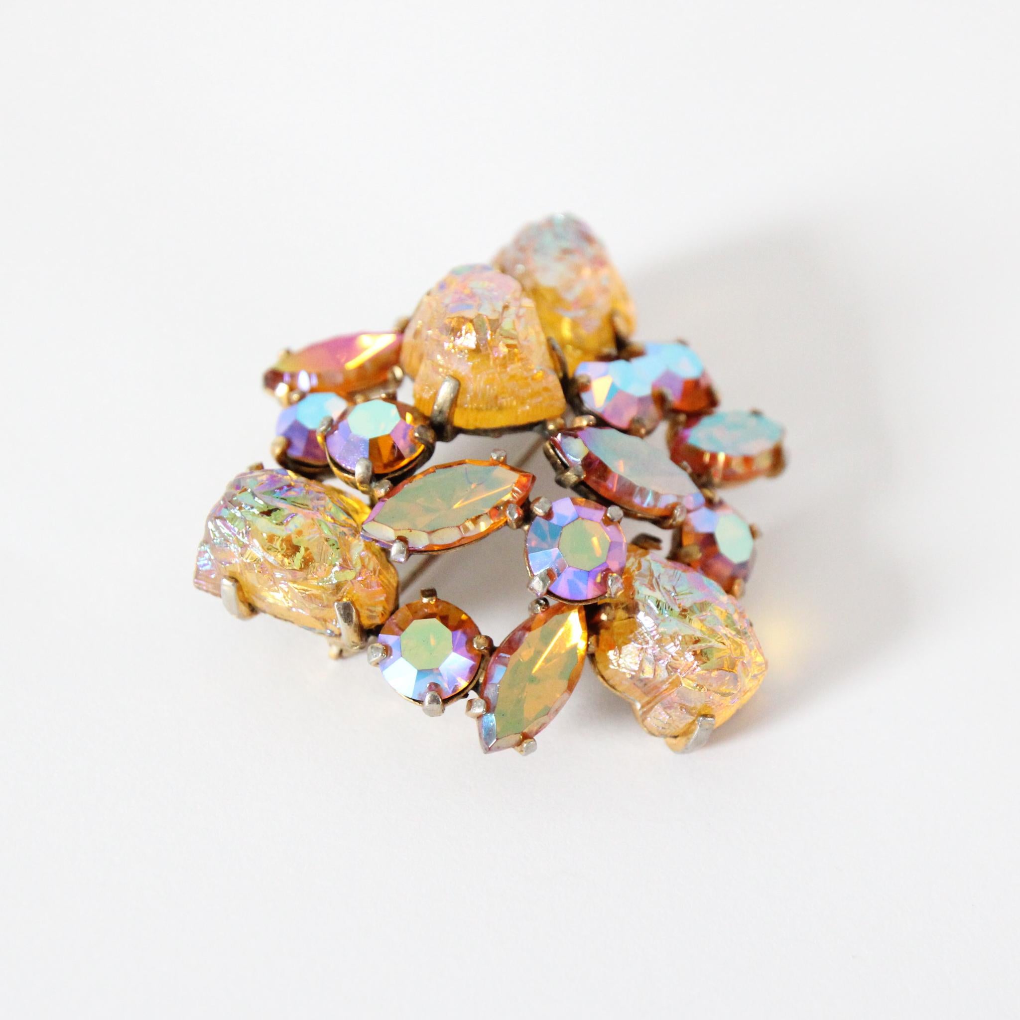 Este impresionante broche Schiaparelli de los años 50, en los tonos más sobrecogedores de estrás naranja iridiscente y rosa, engastado sobre rocas de lava naranja iridiscente, es una pieza rara de contemplar.
El broche tiene un diseño curvo y