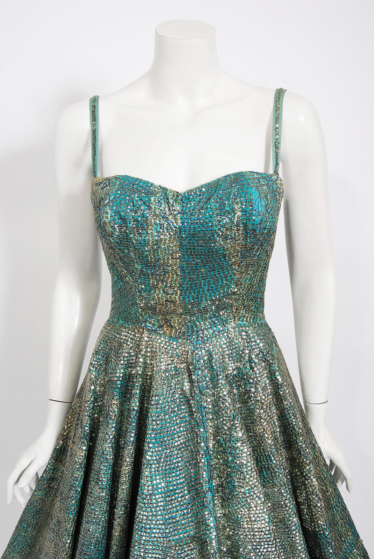 Con su precioso color azul turquesa y su silueta impecable, este vestido azteca mexicano con estampado tiki tiene la elegancia desenfadada por la que eran conocidos los años 50. El tejido en sí es una obra maestra: algodón de peso medio en un tono