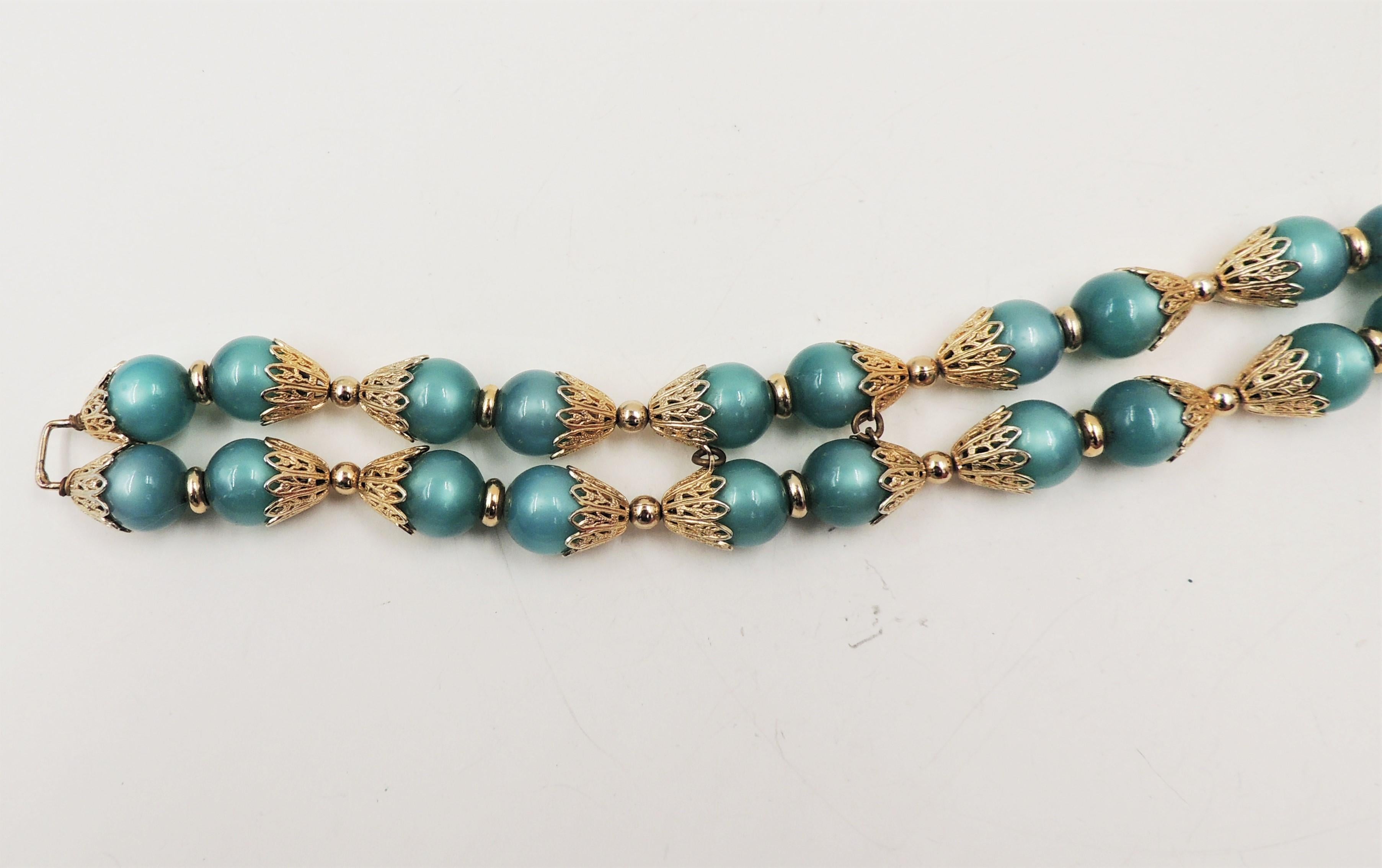 1950s goldtone filigree with green resin moonglow beaded two strand bracelet with fold over clasp. Marked 
