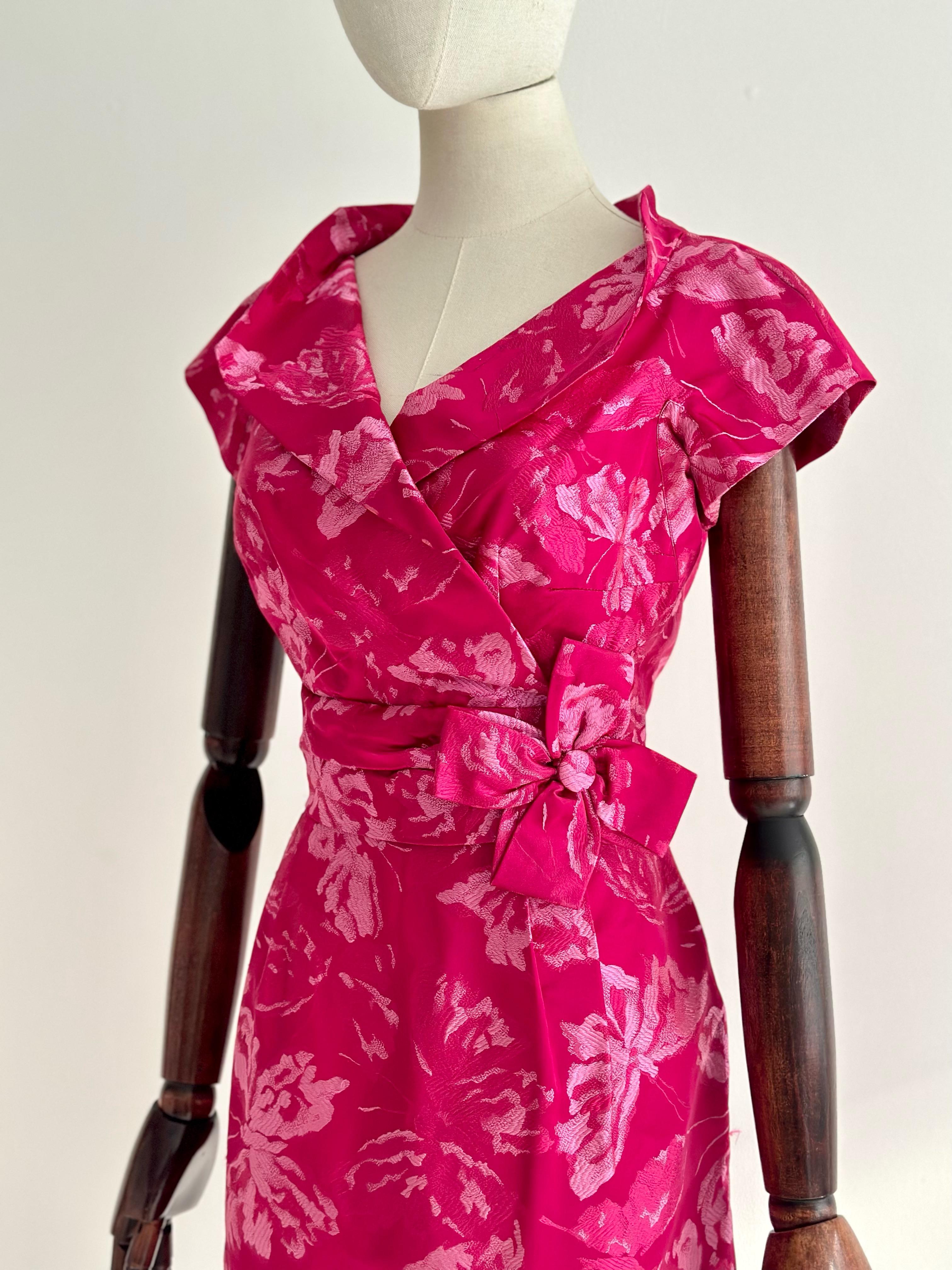 A marvel to behold, this original 1950's silk brocade dress in a vibrant shade of fuchsia pink with rose pink accents, in a wonderfully intricate butterfly pattern, is just the piece to add to your vintage collection.   

The V shaped neckline of