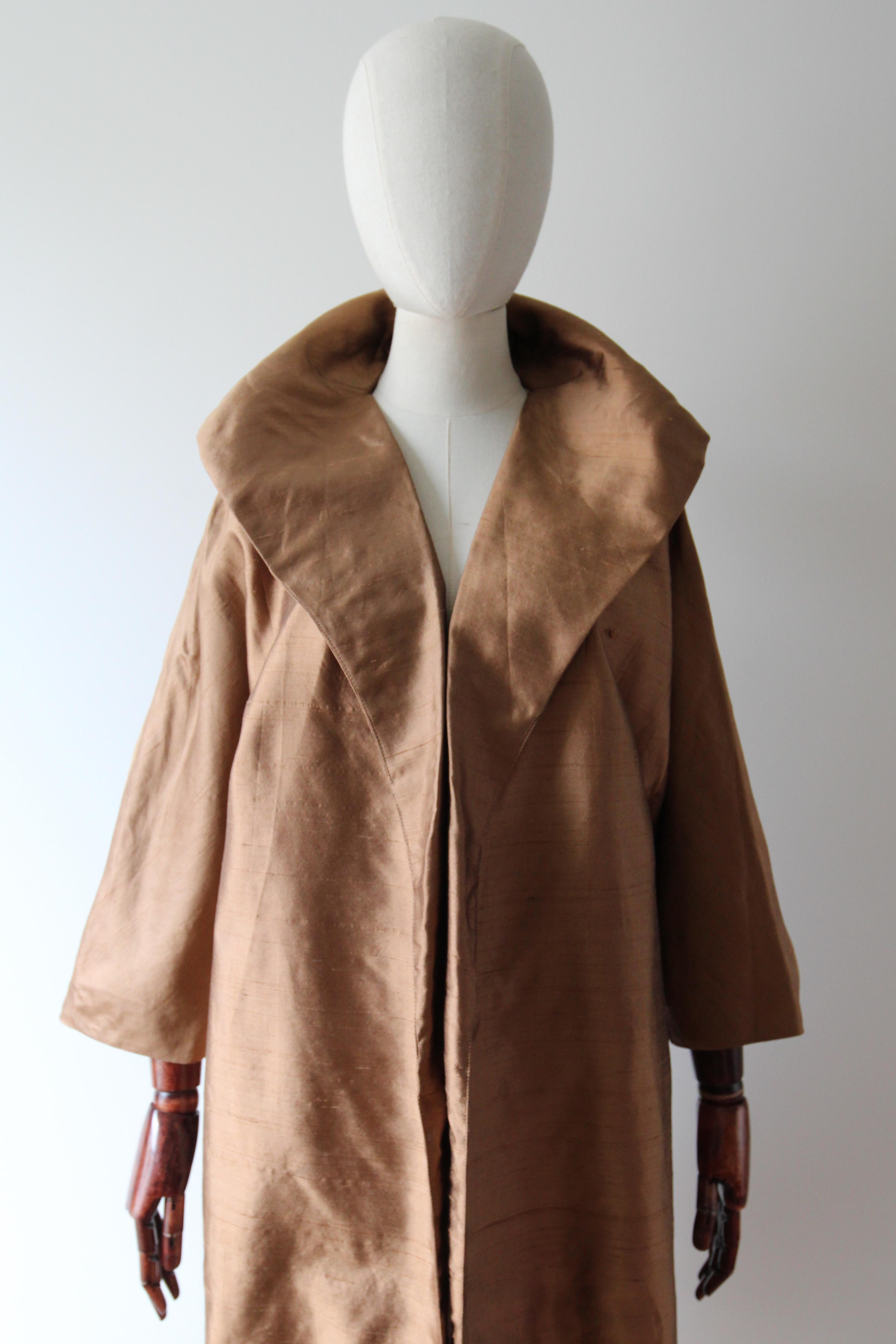 Rendered in the most sumptuous shade of tawny brown raw silk, this original 1950's silk duster coat, is the perfect addition to your vintage collection. 

The elegant V shaped open neckline is framed by a wide shawl collar which conceals the