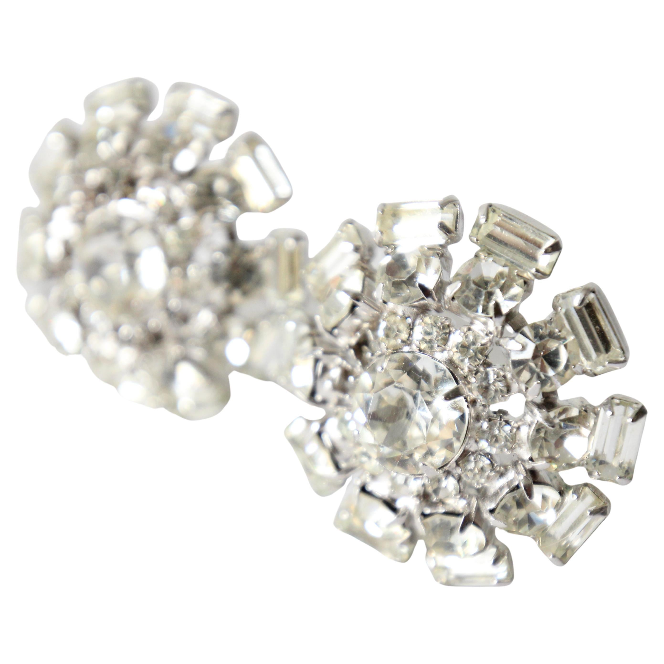 This breathtaking pair of 1950's clip on earrings, on silver toned metal bases, made up of claw set silver glass rhinestones in a tiered sunburst design surrounded a large central claw set rhinestone,  are the perfect touch of sparkle to your
