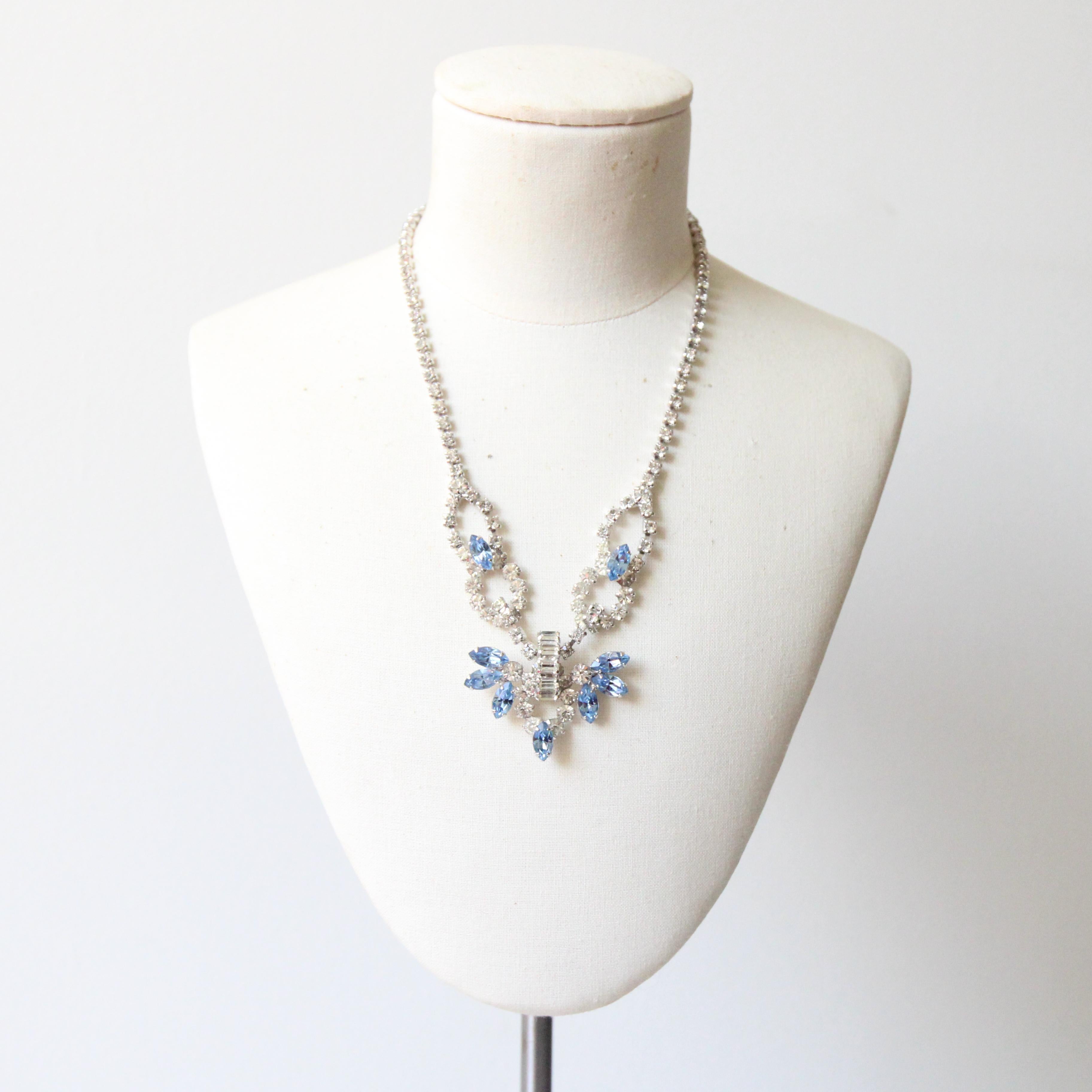 This elegant 1950's necklace, made up of silver and sky blue claw set glass rhinestones, is the perfect finishing touch to any outfit.

The decorative rhinestone linked chain boasts an adjustable length with a hook feature. The central design is